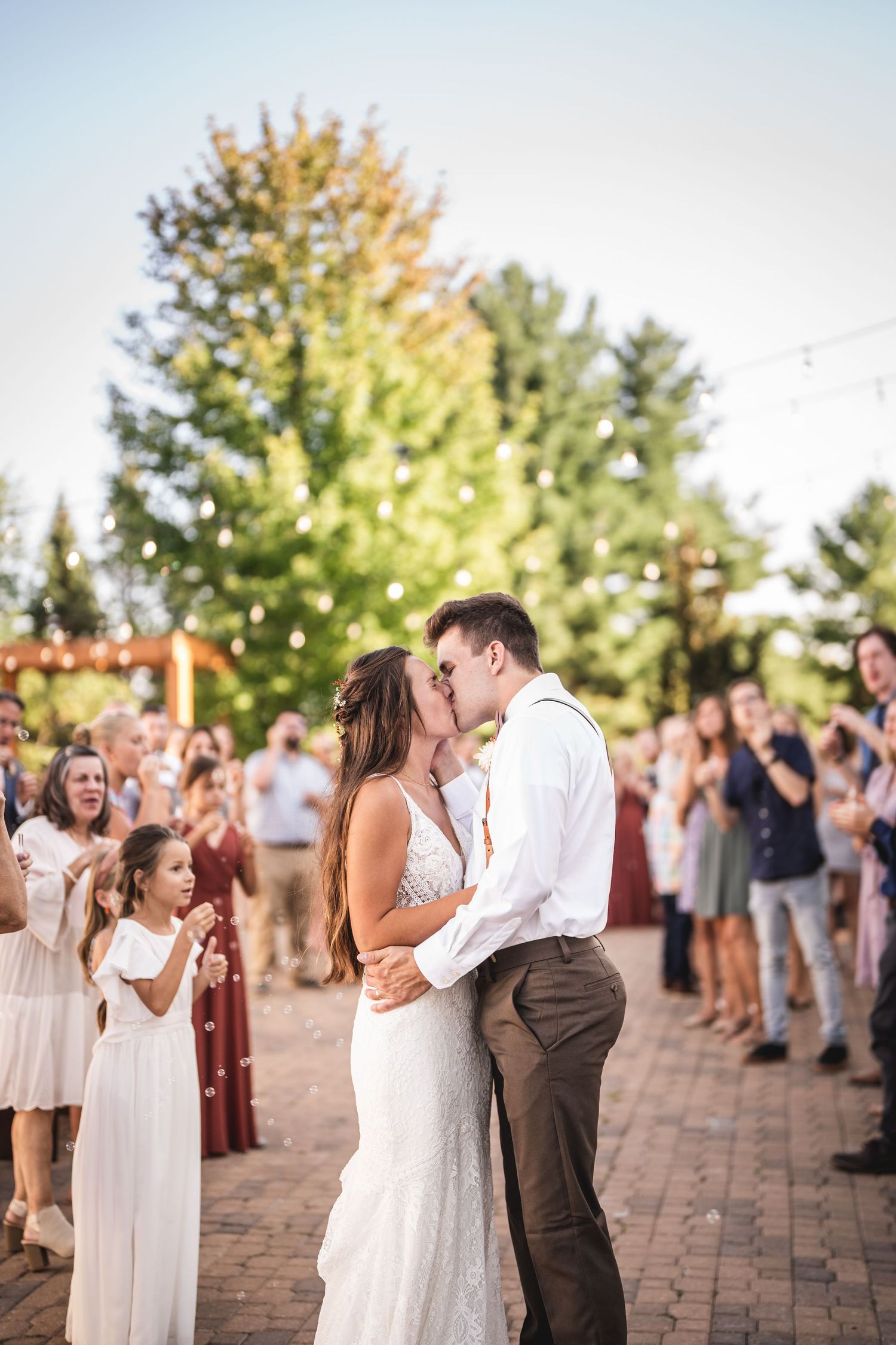 Guests celebrate and cheer during an outdoor wedding ceremony at sunset.