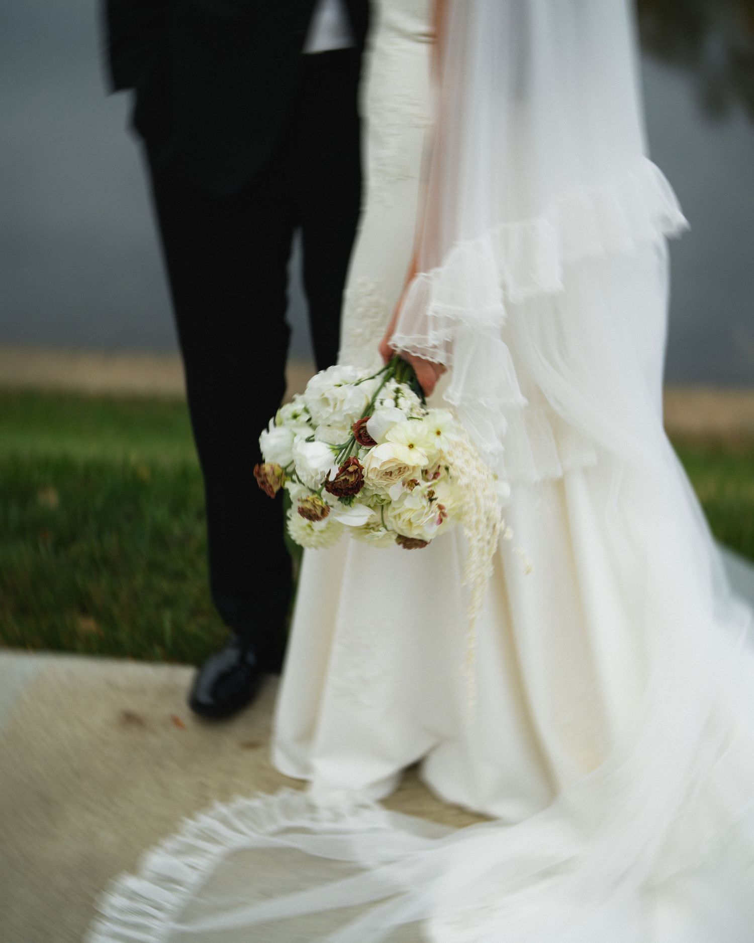 Close-up of white bridal bouquet against flowing wedding dress.