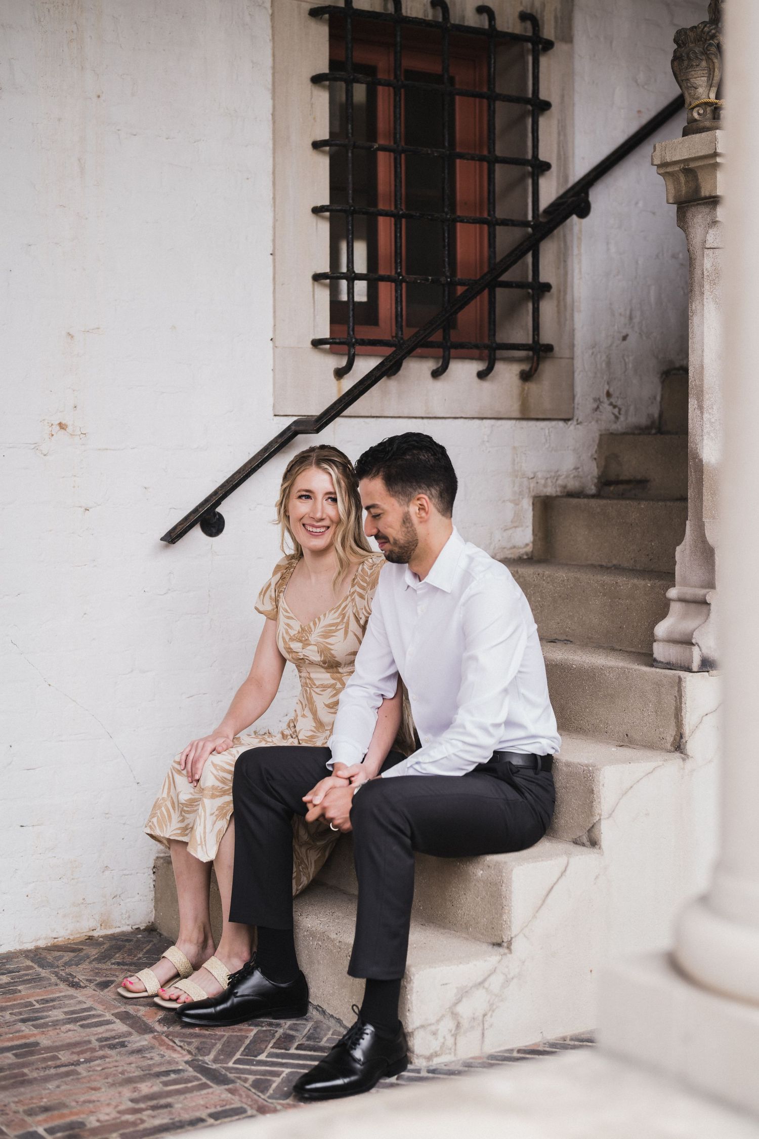 Couple sitting together on stone steps of historic building.