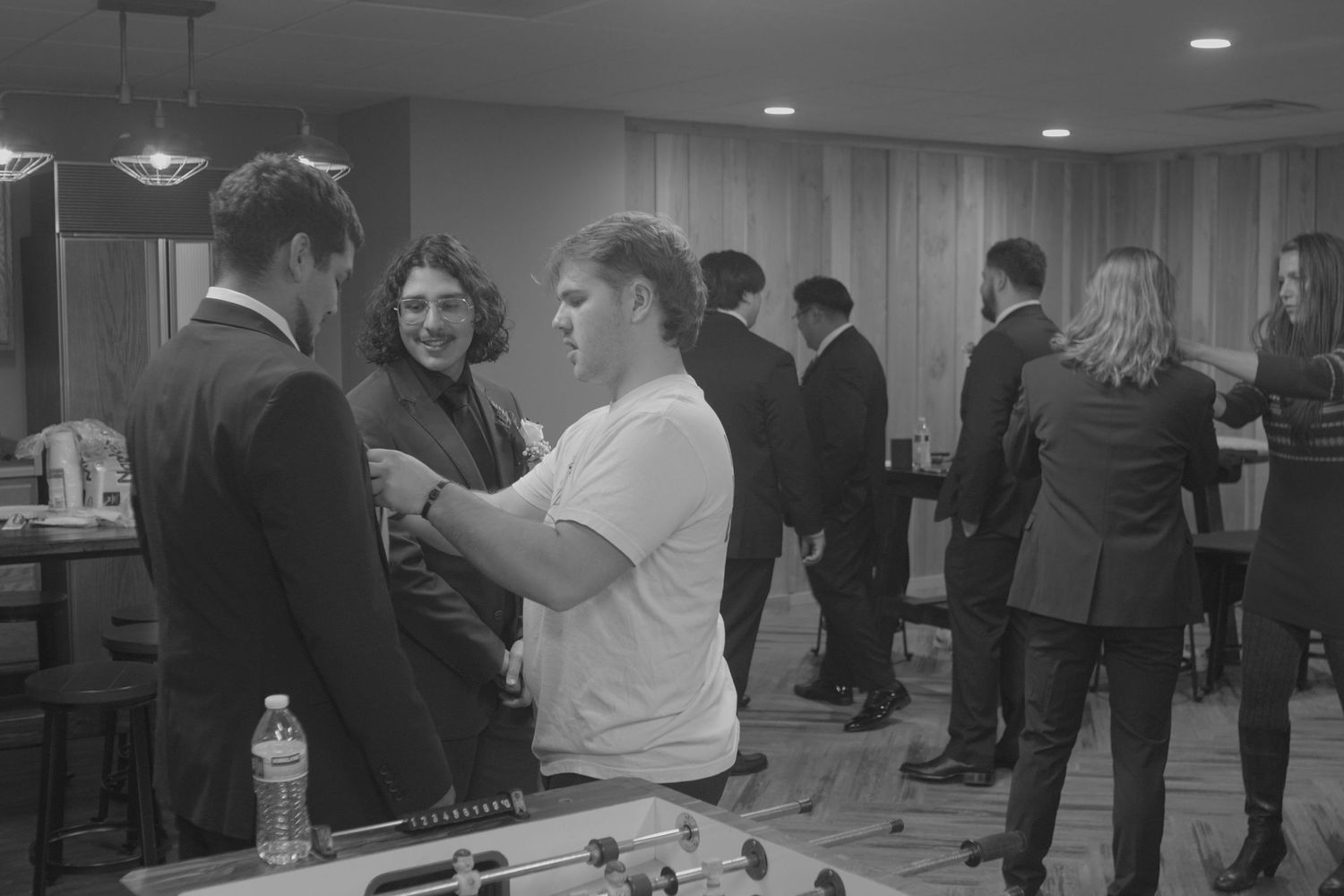 Wedding guests mingling in a reception hall with dim lighting.