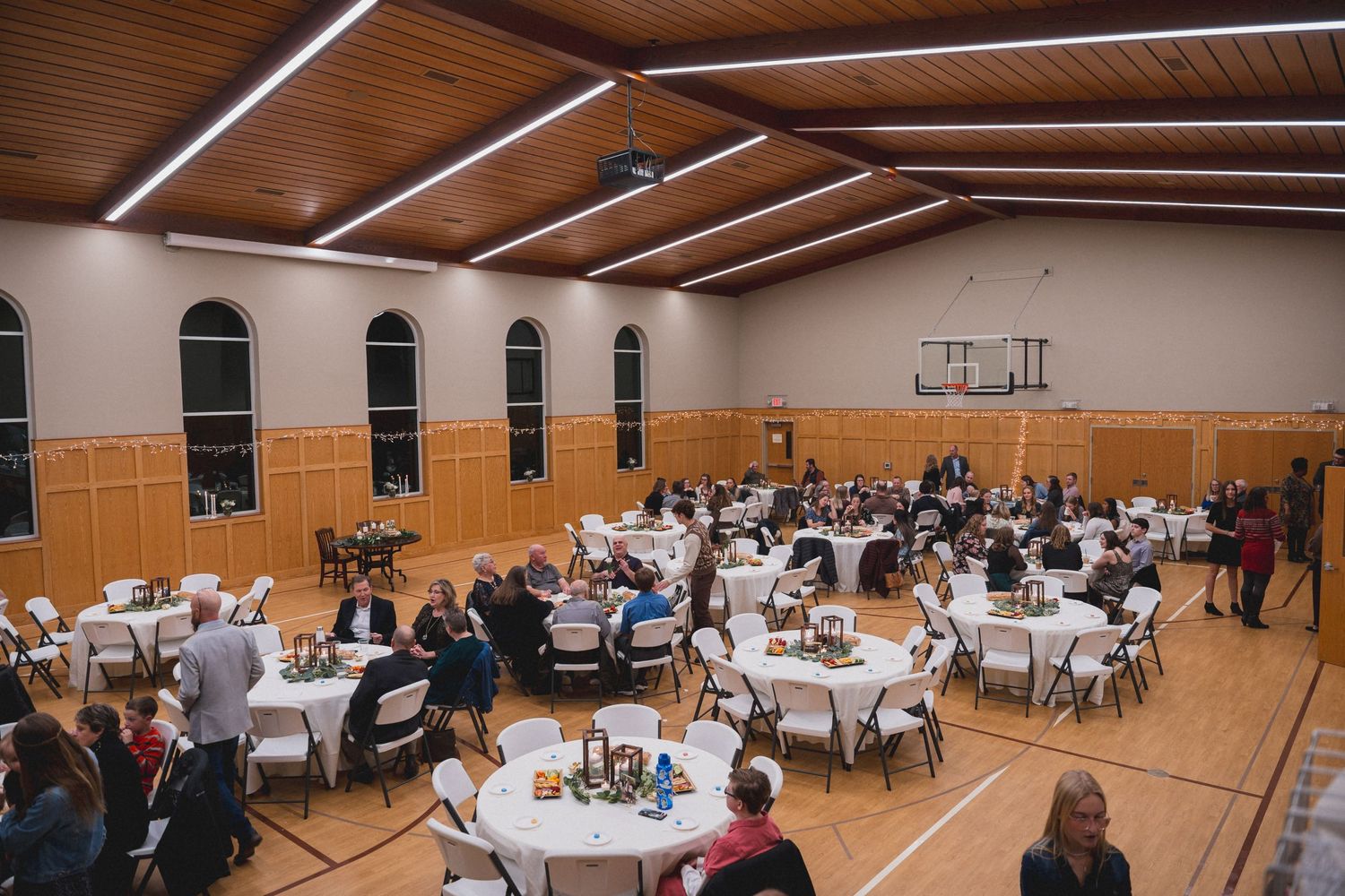 Large church hall set up with round tables and chairs for a wedding reception.