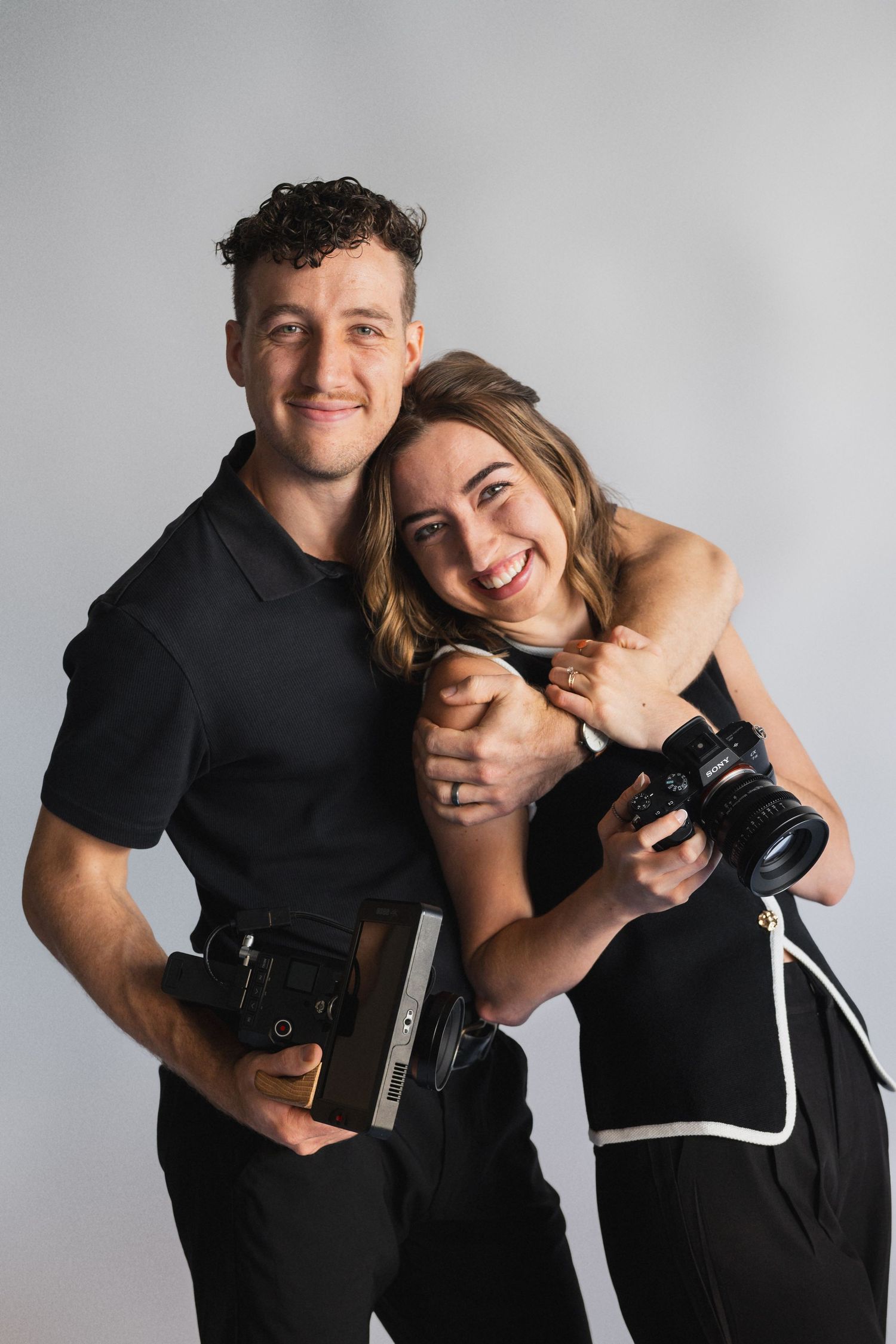 Professional photographers in matching black outfits pose with camera equipment.