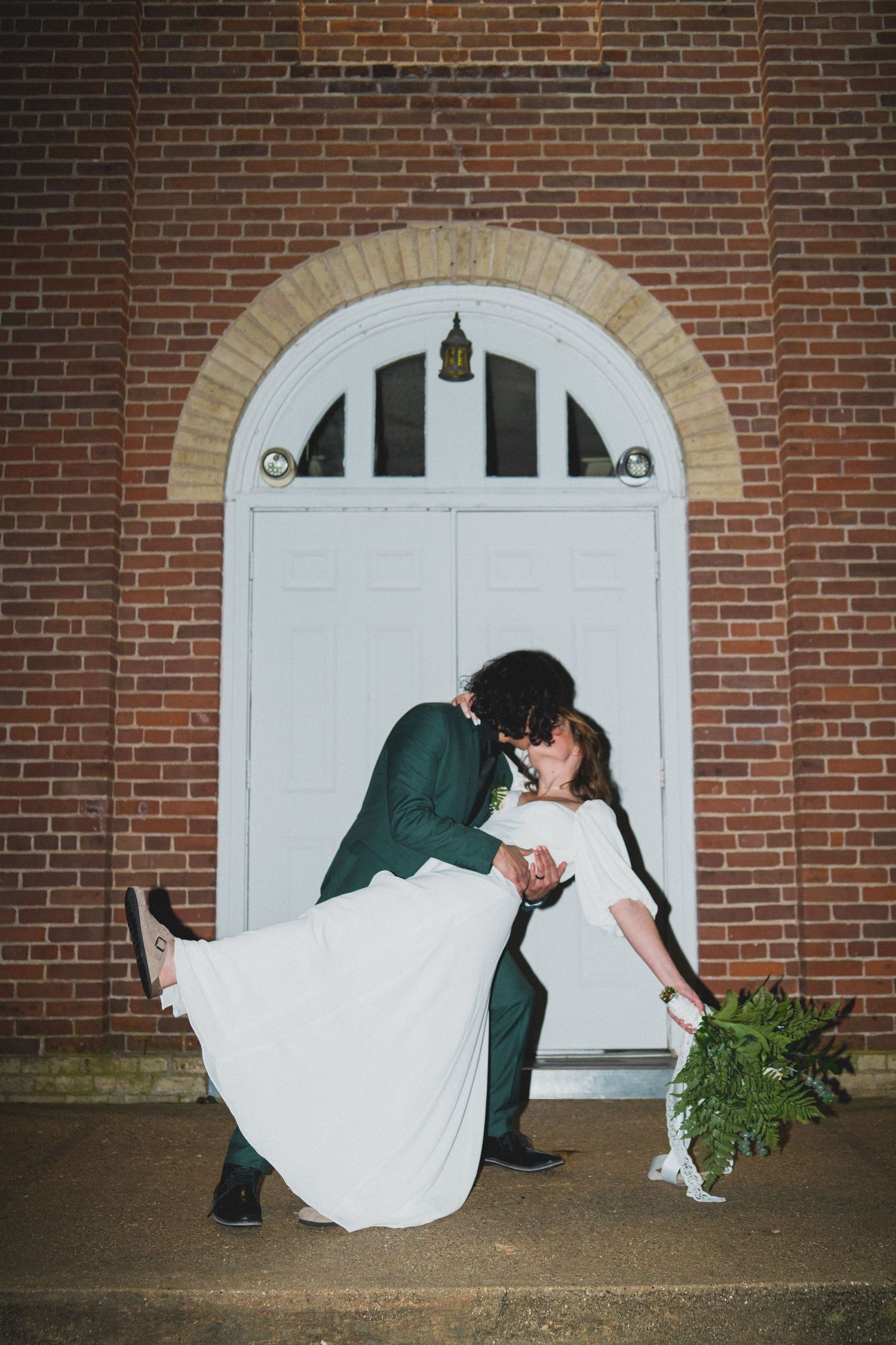 Sequence of romantic dip kisses between newlyweds against a brick wall and white doorway.
