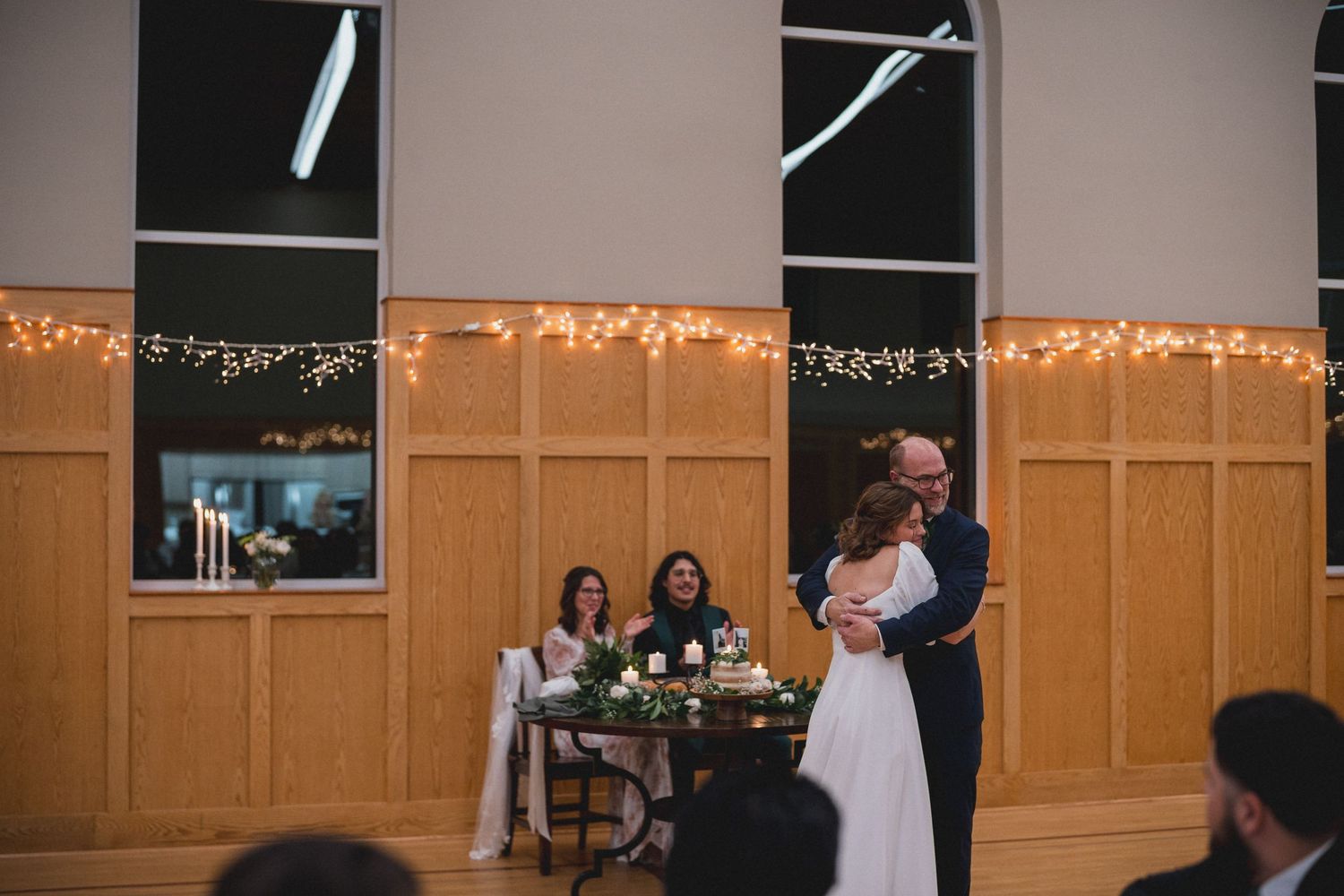 Wedding reception venue with string lights and wooden paneled walls.