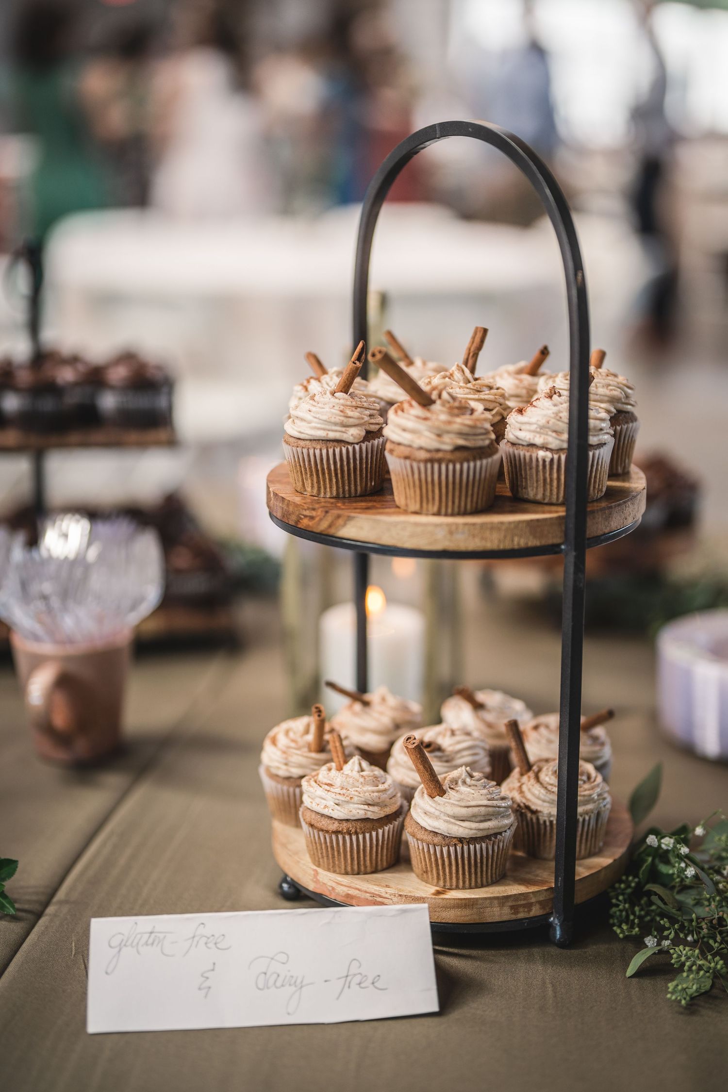Two-tiered display stand with decorated cupcakes at a wedding dessert table.