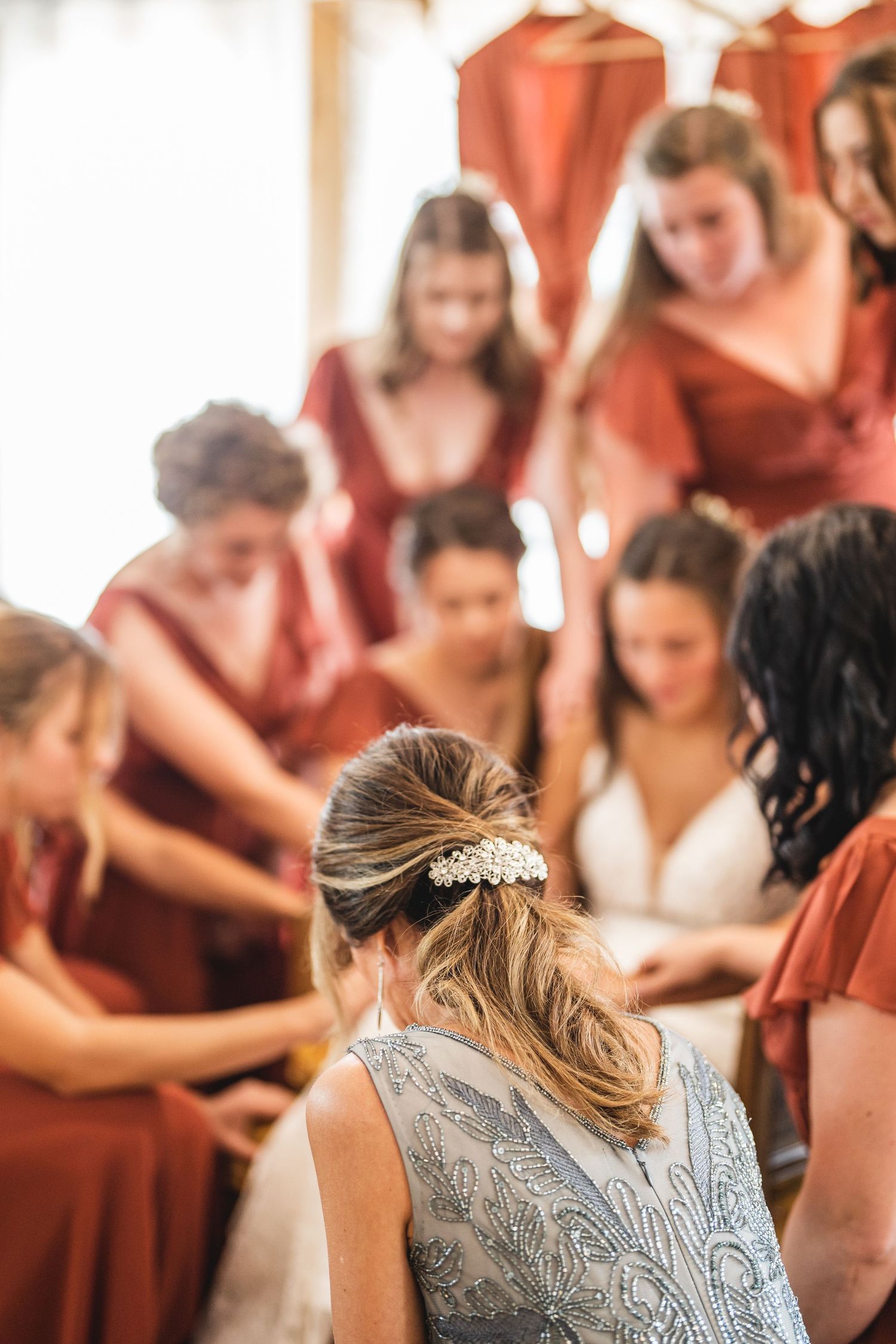 Wedding preparation scene with bridesmaids in coral dresses gathering around.