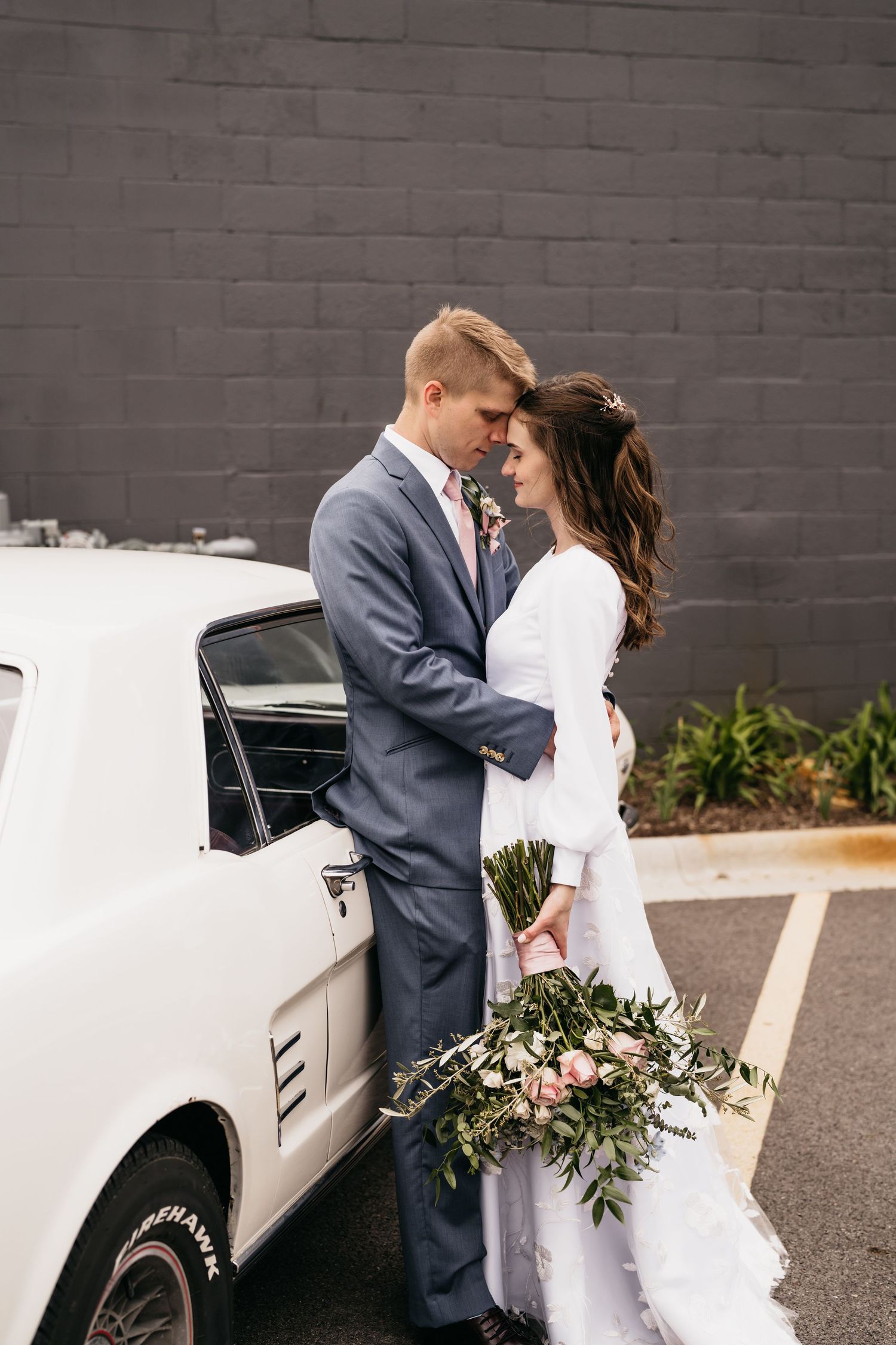 Romantic moment by vintage white car with bridal bouquet.