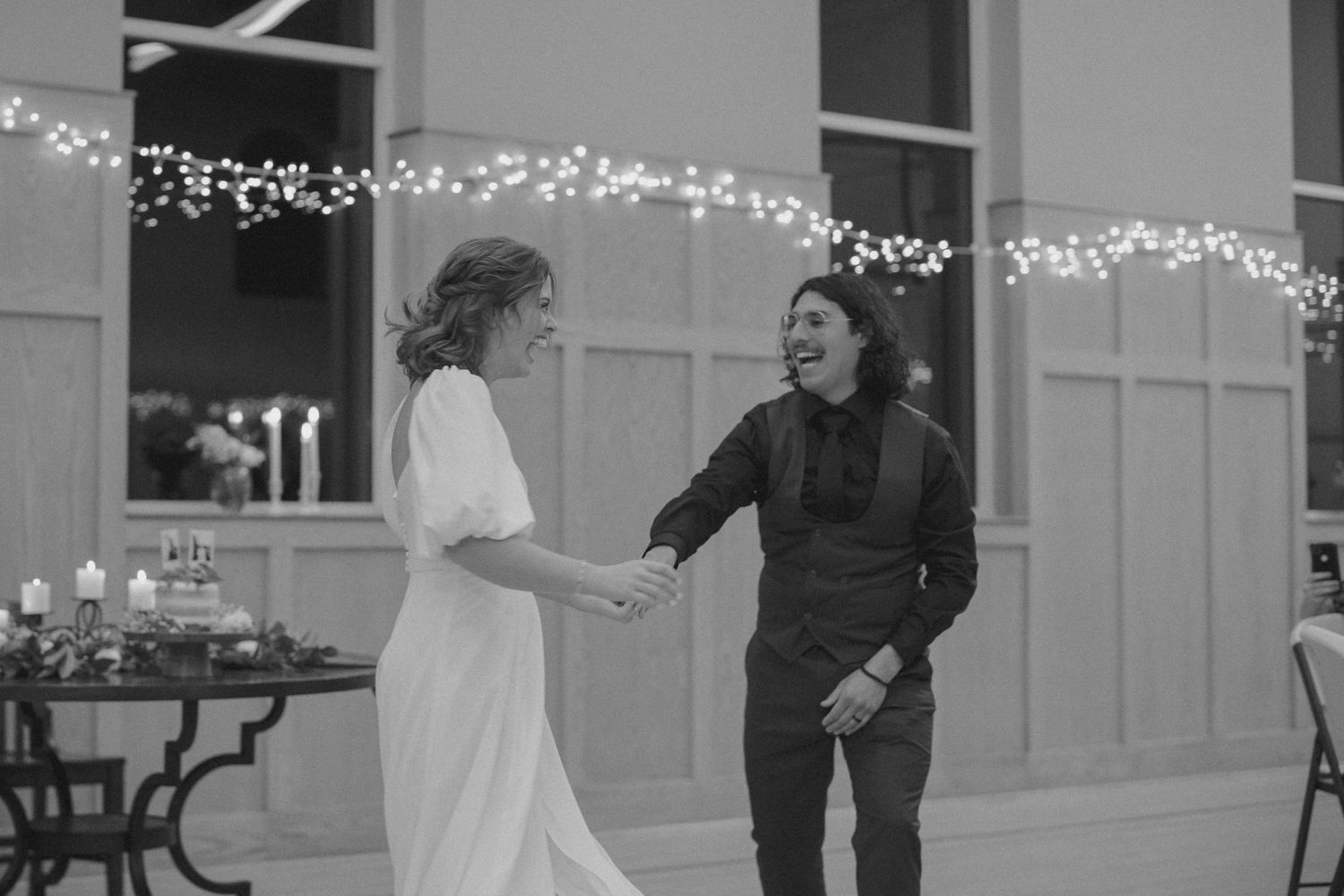Wedding reception dance with string lights decorating the wooden paneled walls.