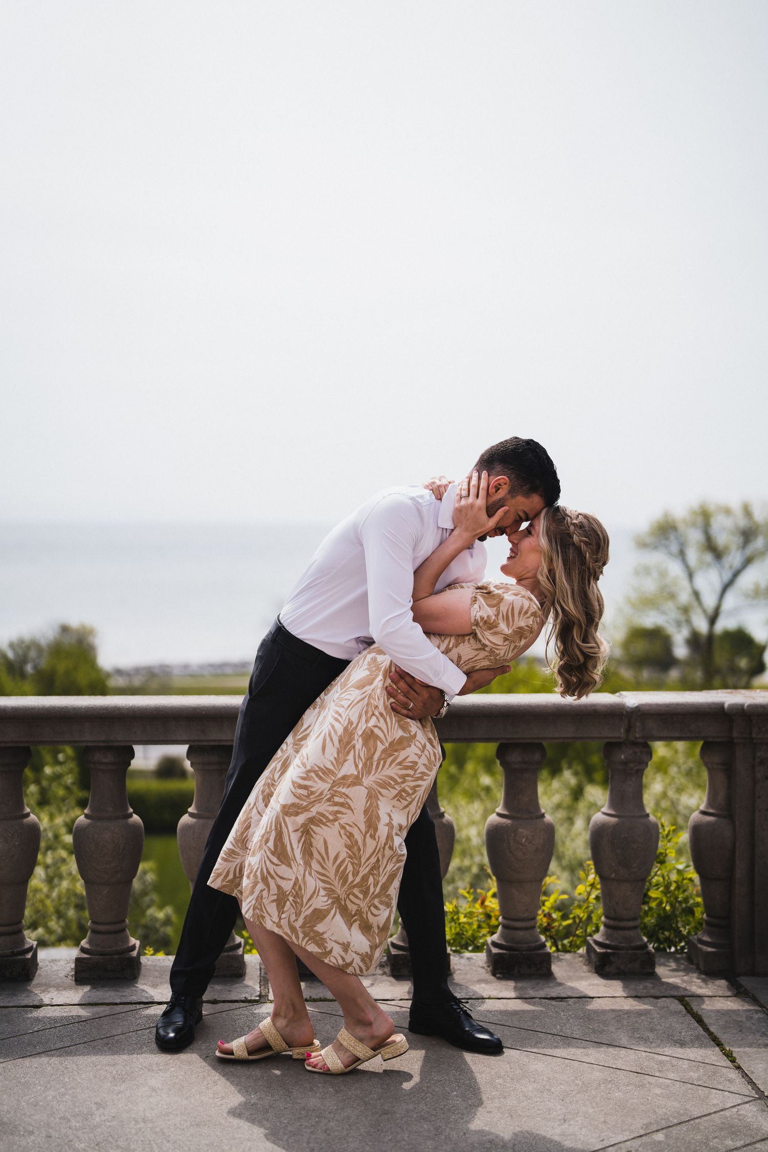 Romantic dip pose on stone balcony of historic building during engagement photoshoot.