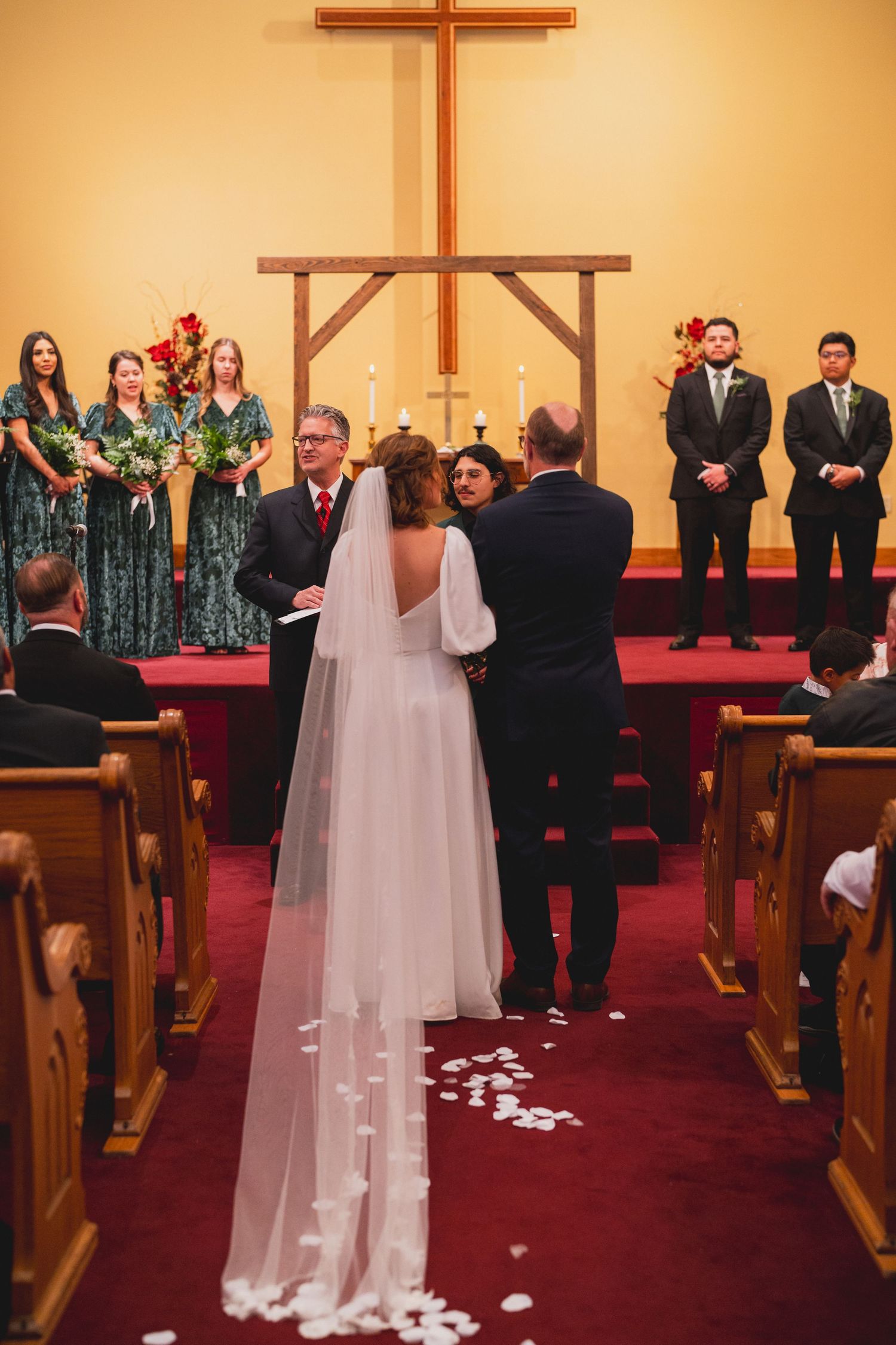 Traditional church wedding ceremony with wooden cross and red carpet aisle.
