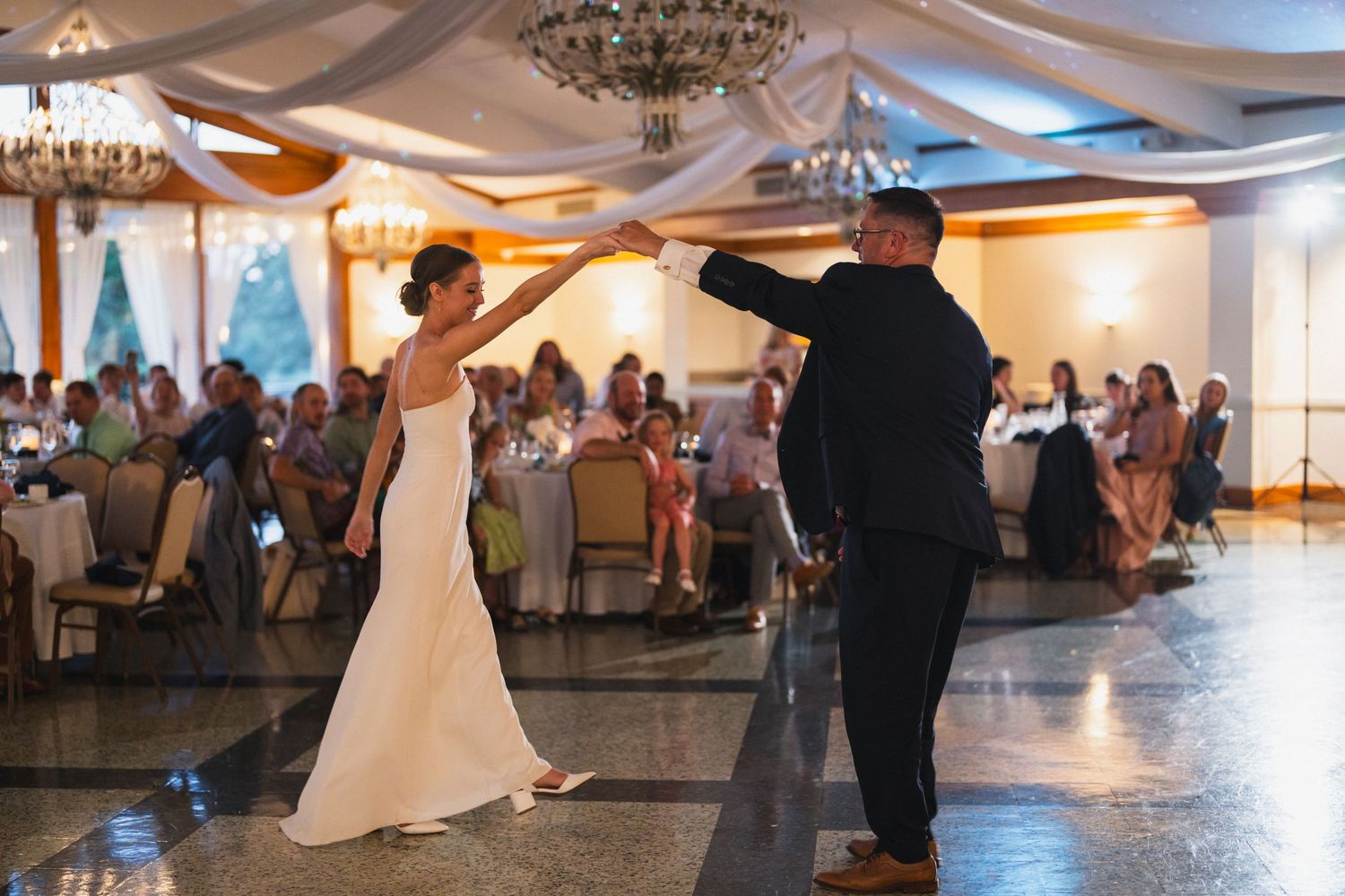 Bride and groom share their first dance in an elegant decorated wedding reception ballroom.