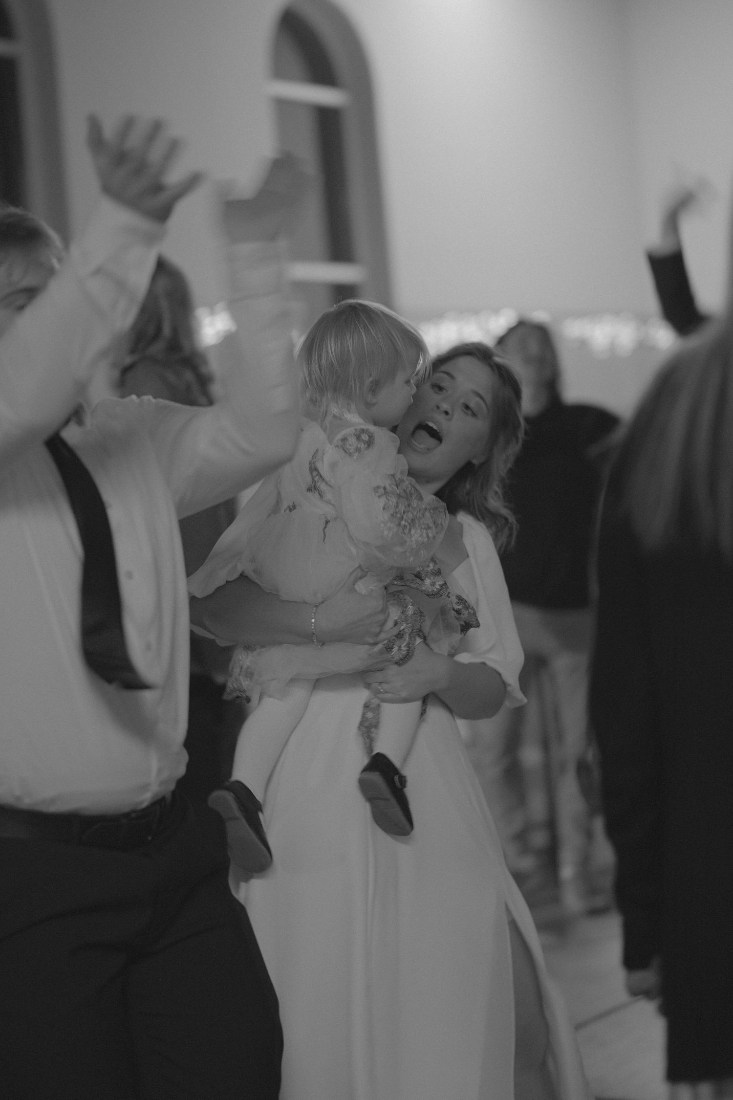 Dancing couples celebrate at an indoor event with ambient lighting.