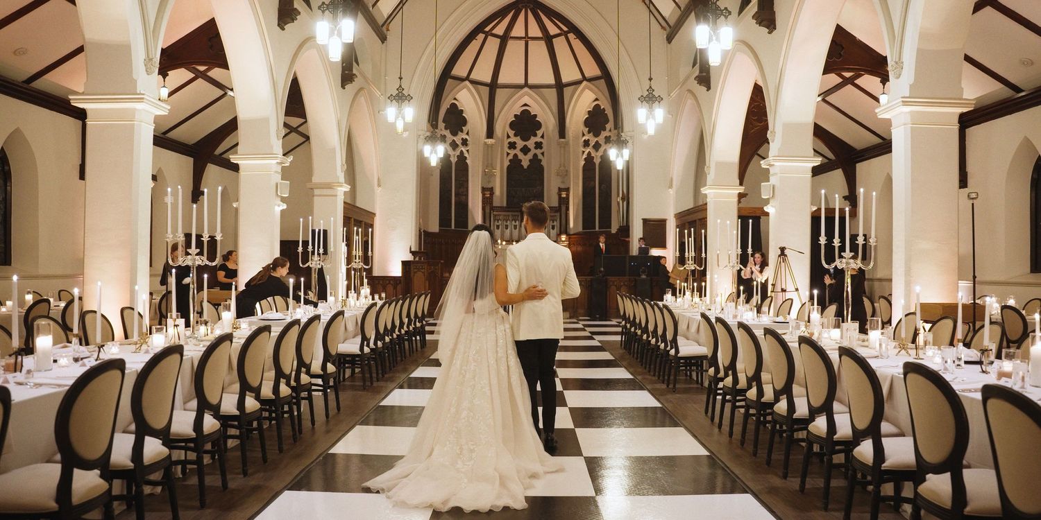 Elegant church interior with checkered floor and long tables set for a wedding reception.