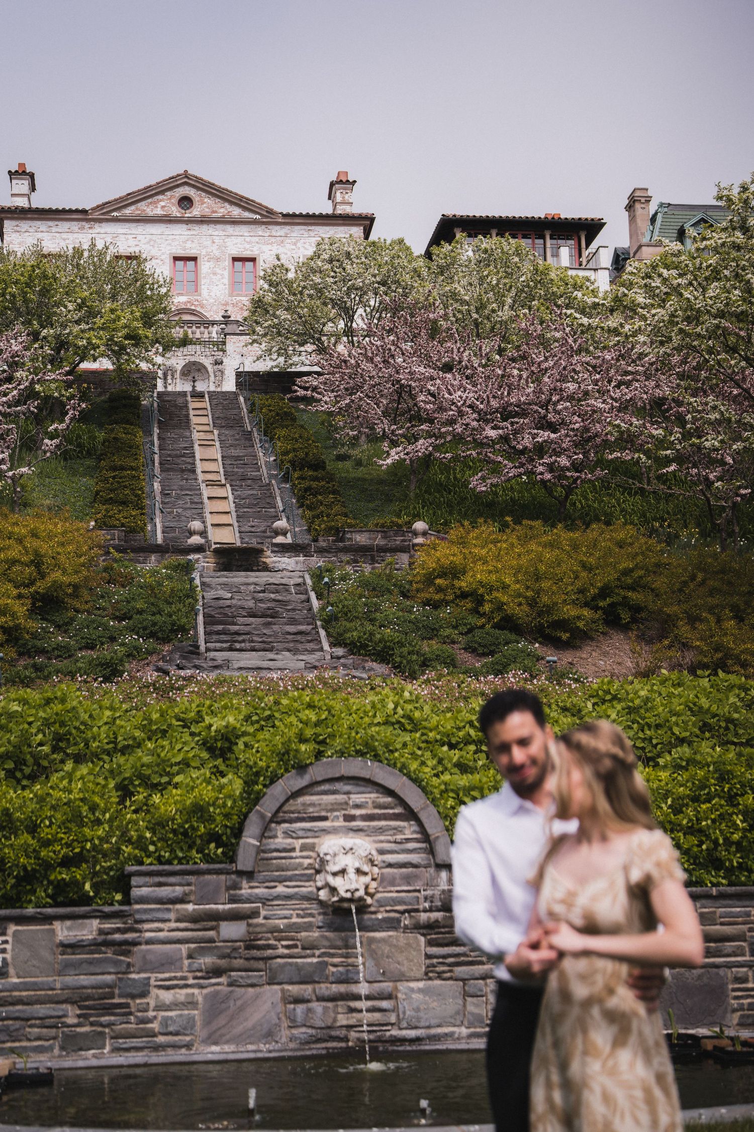 Stone staircase leading to historic building with blooming cherry trees in spring.