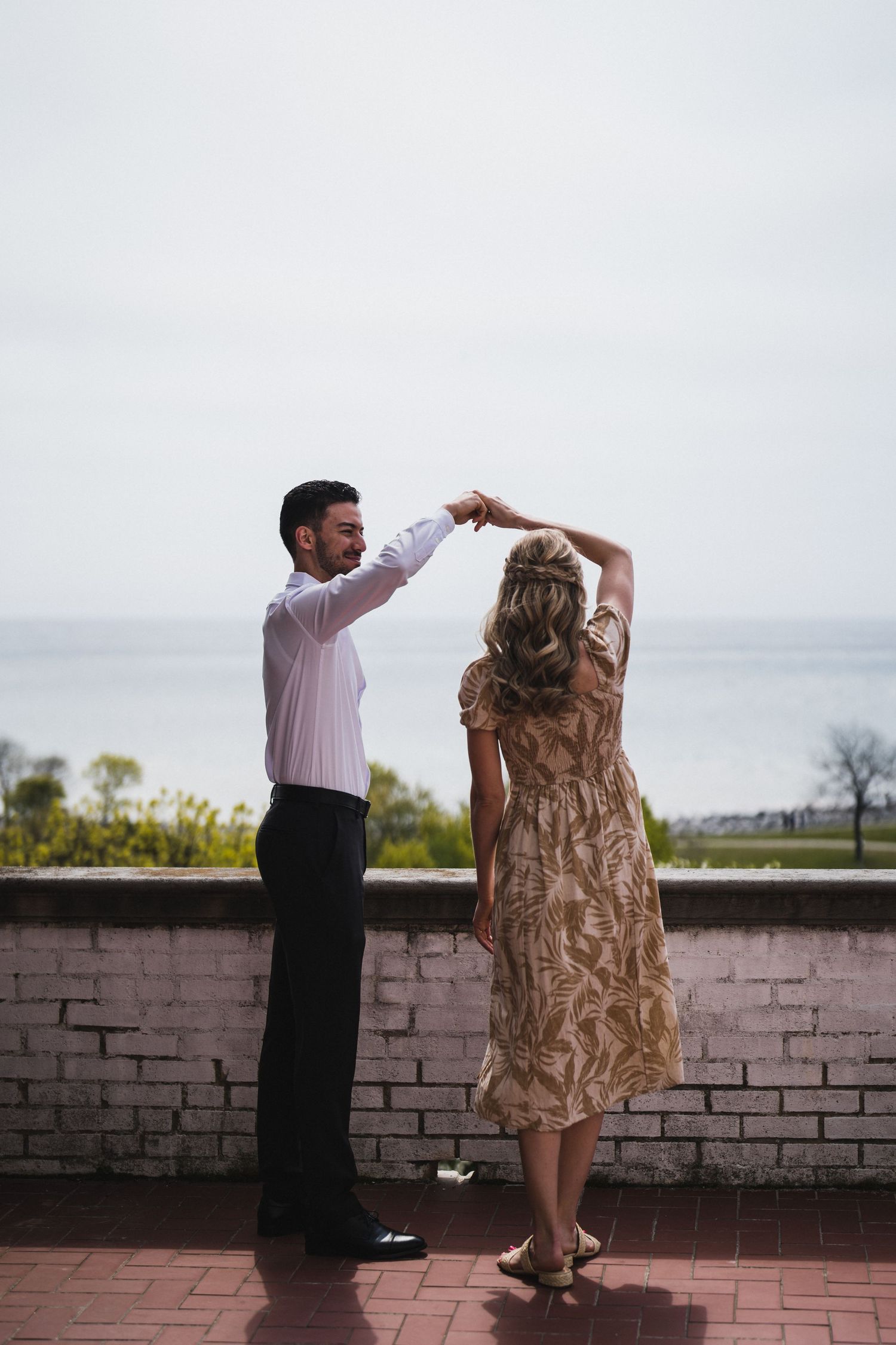 A couple dancing together on a brick patio in a romantic twirling motion.