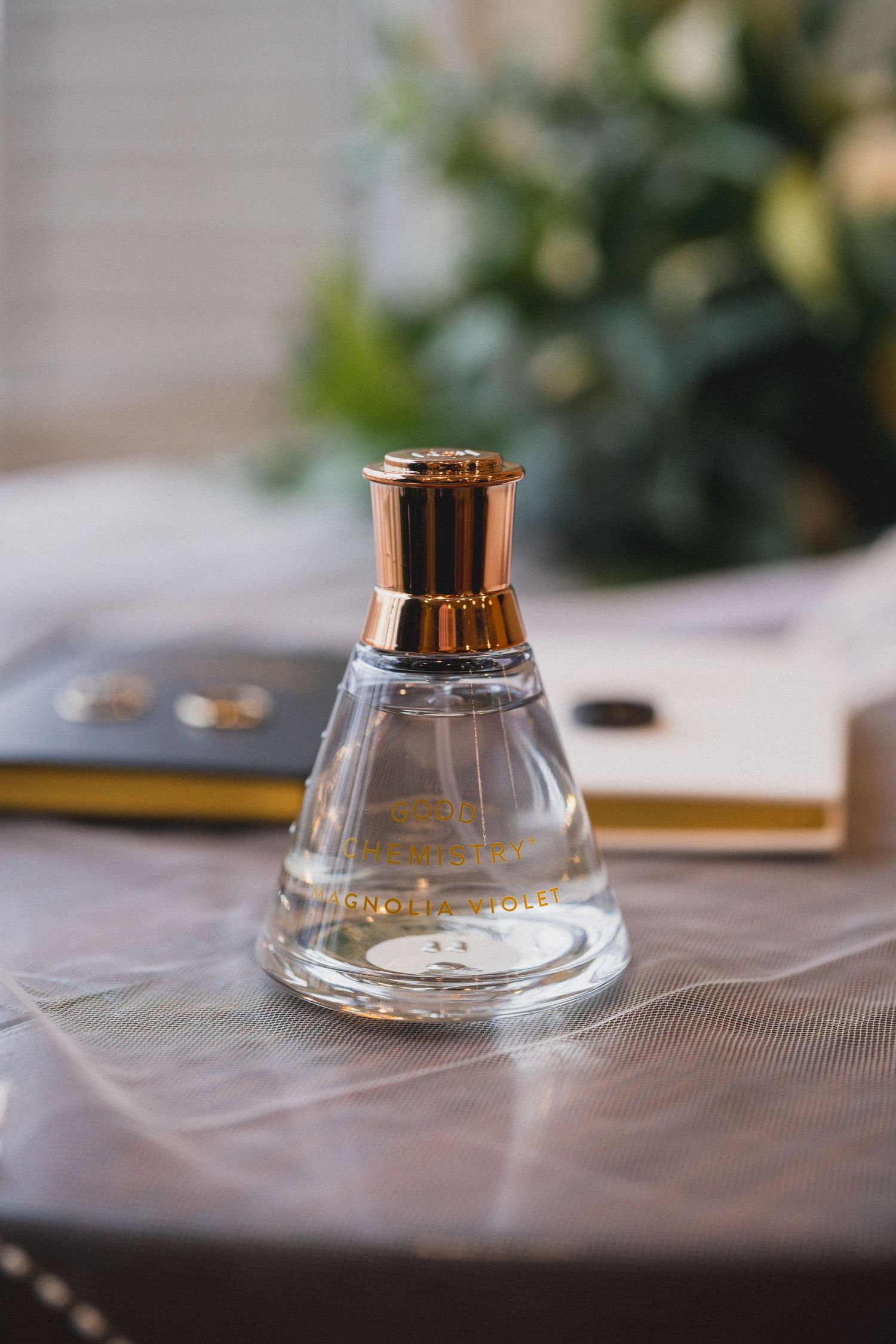 A elegant glass perfume bottle with gold cap photographed on white fabric.