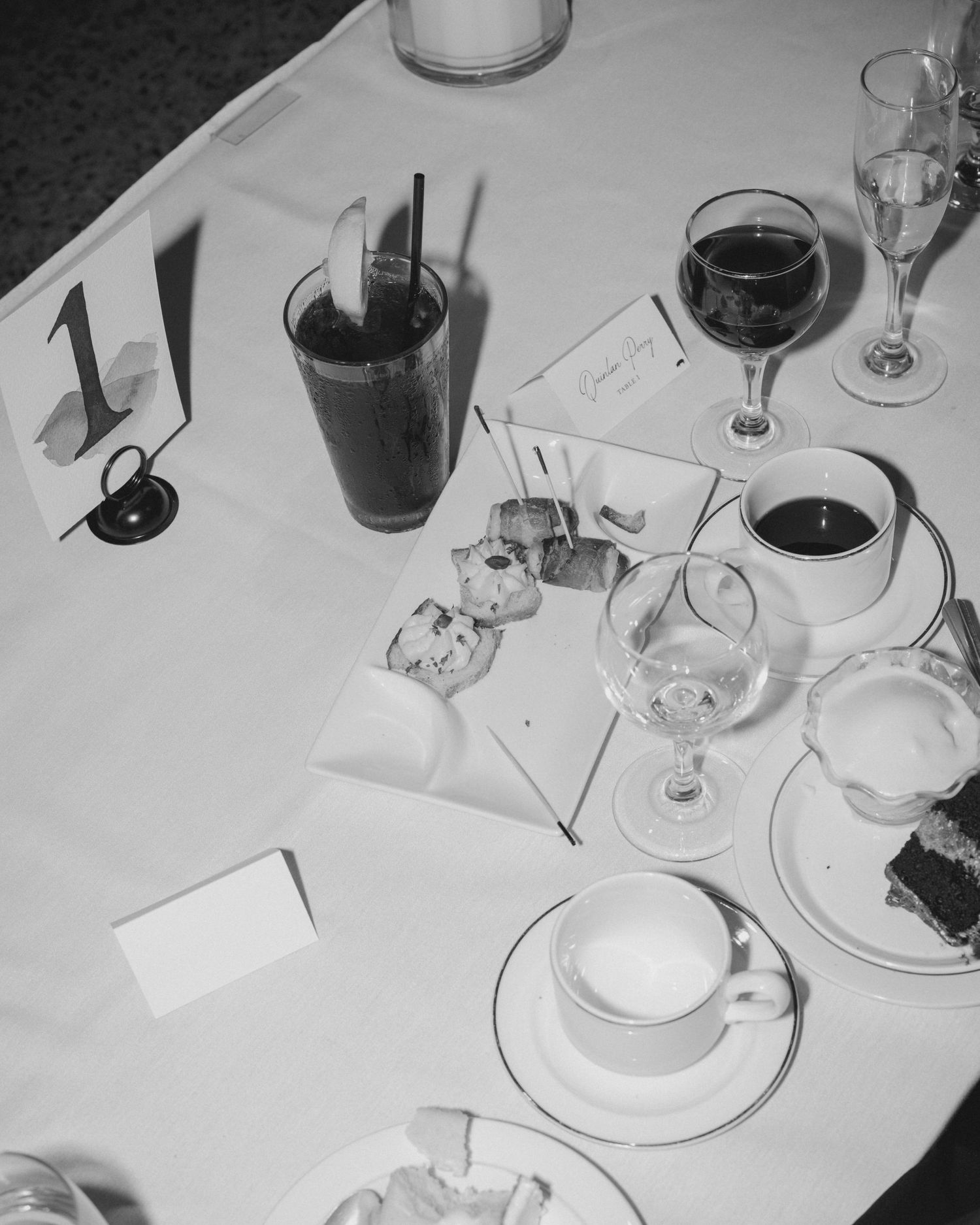 Black and white overhead shot of a wedding reception table with drinks and place settings.