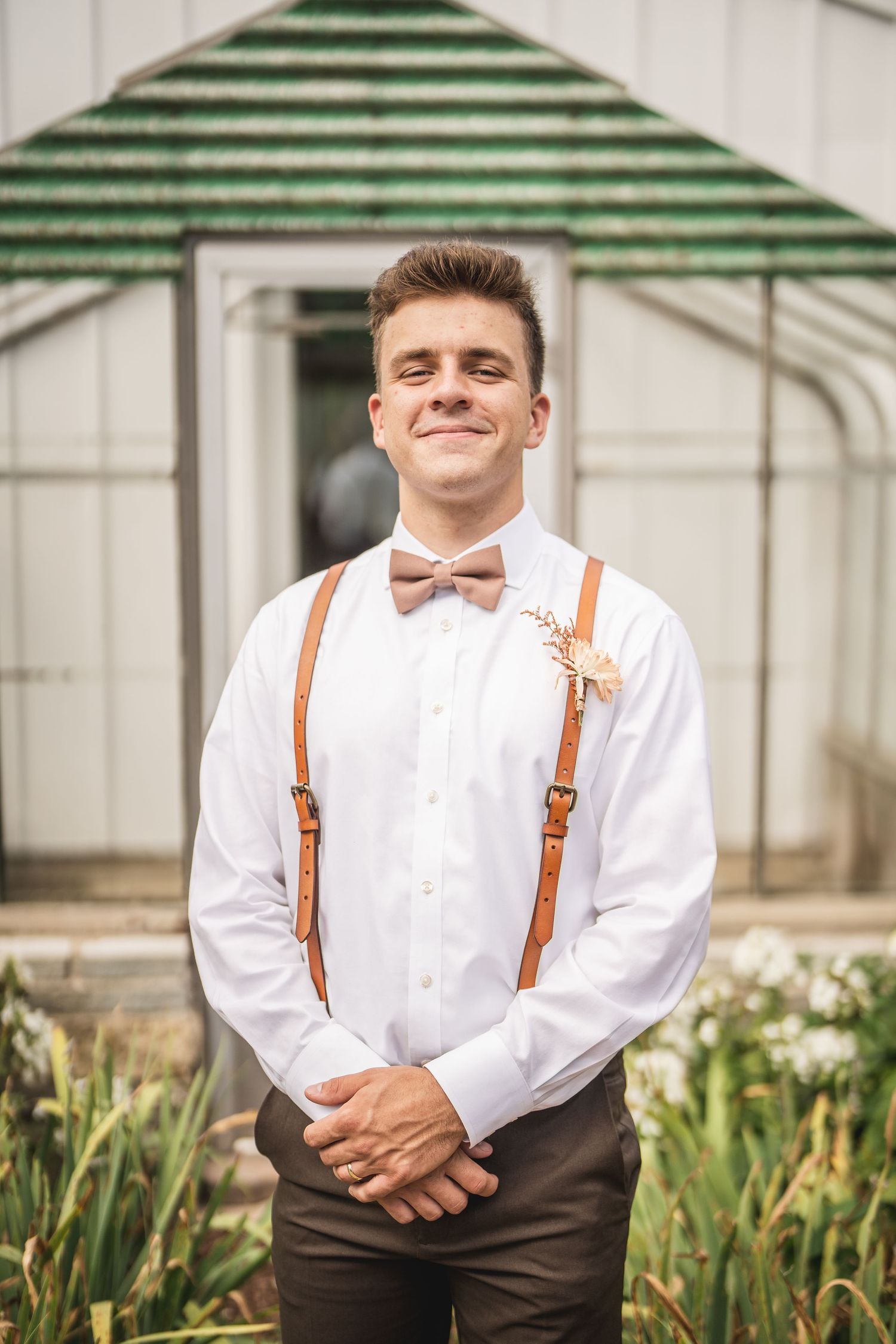 Portrait series of someone in white shirt and suspenders smiling outdoors.