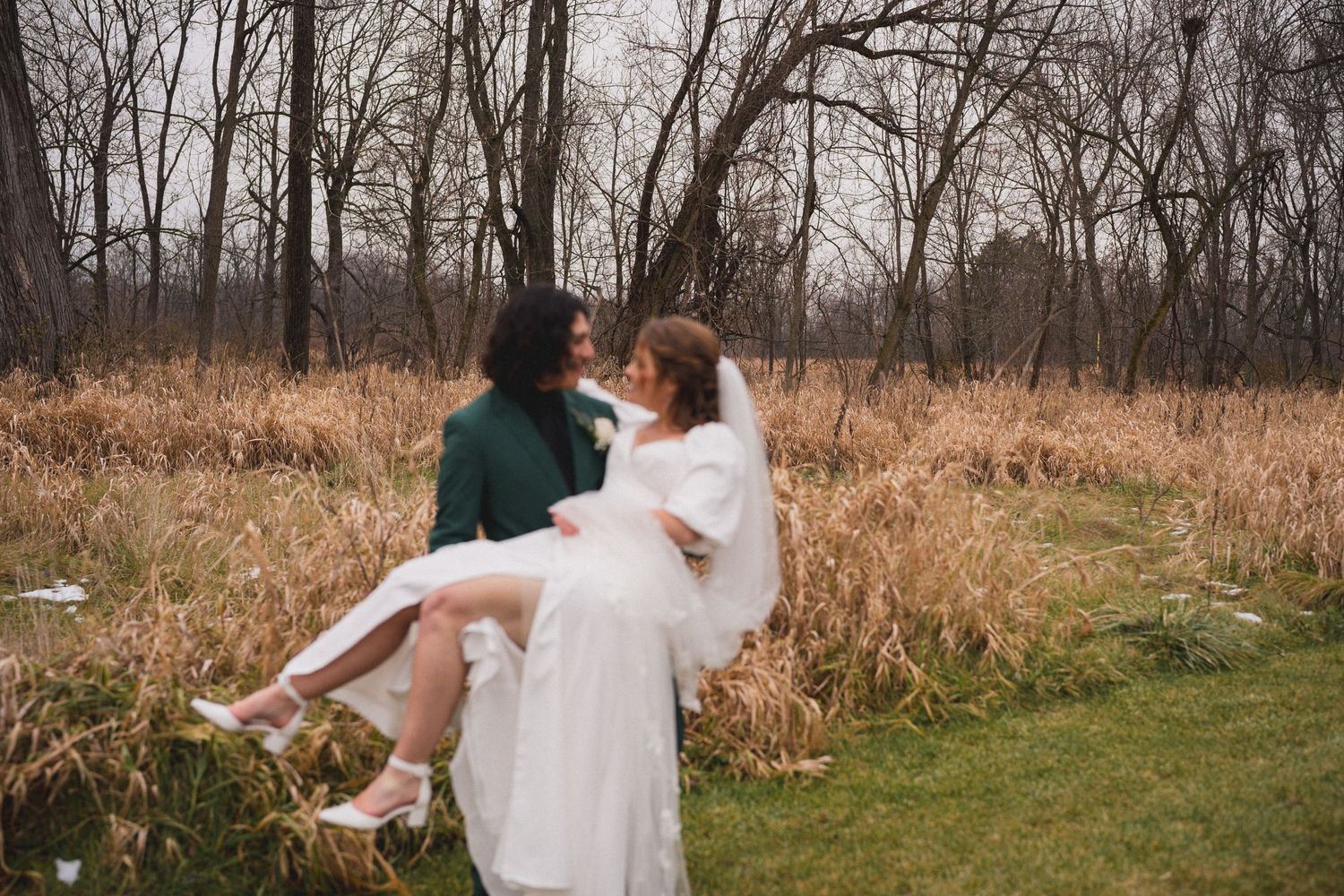 A romantic wedding scene shows a couple in white dress and green suit being carried in a field.