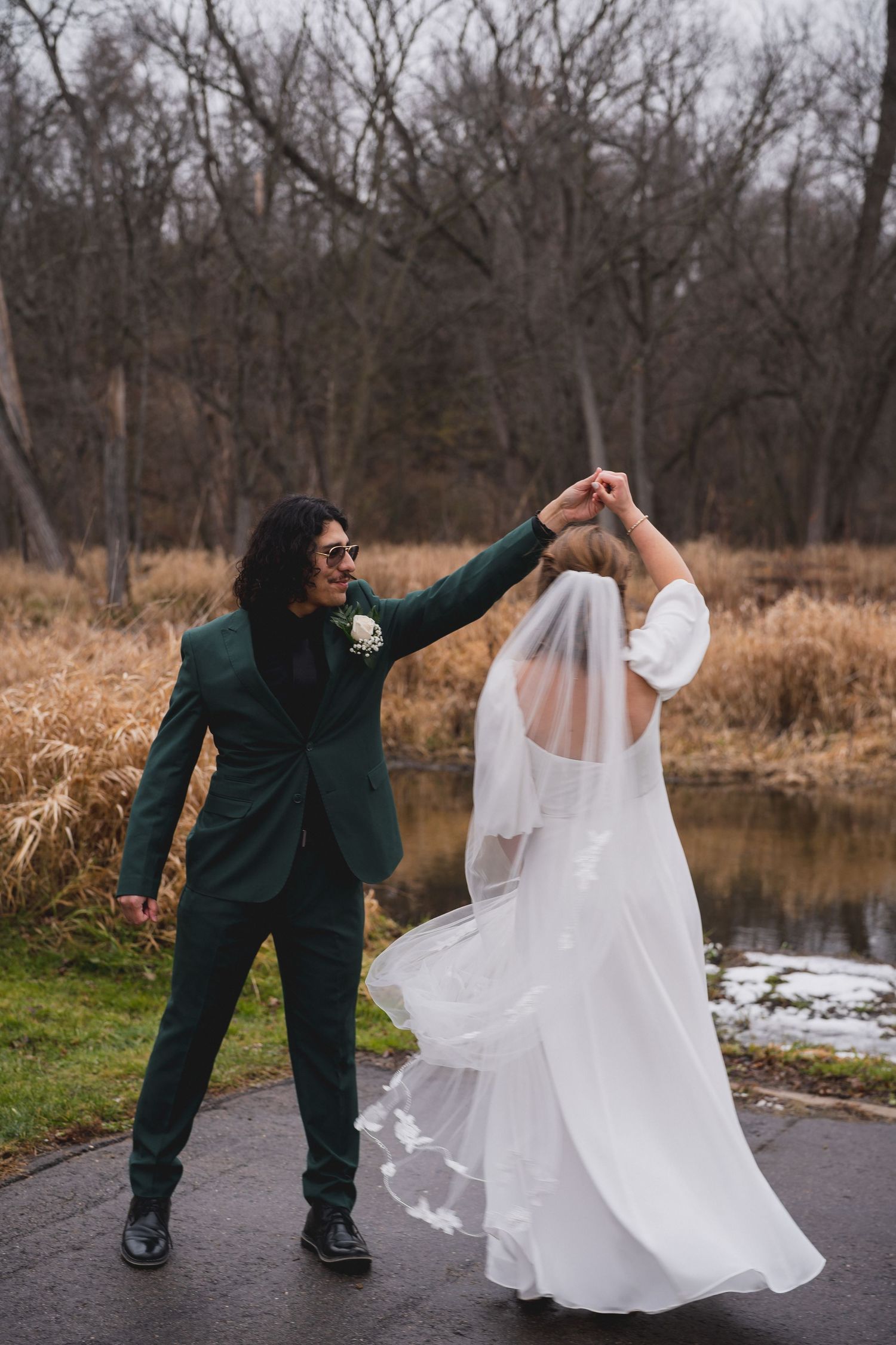 A couple dancing on a path near a pond, with the bride's dress flowing in an elegant spin.