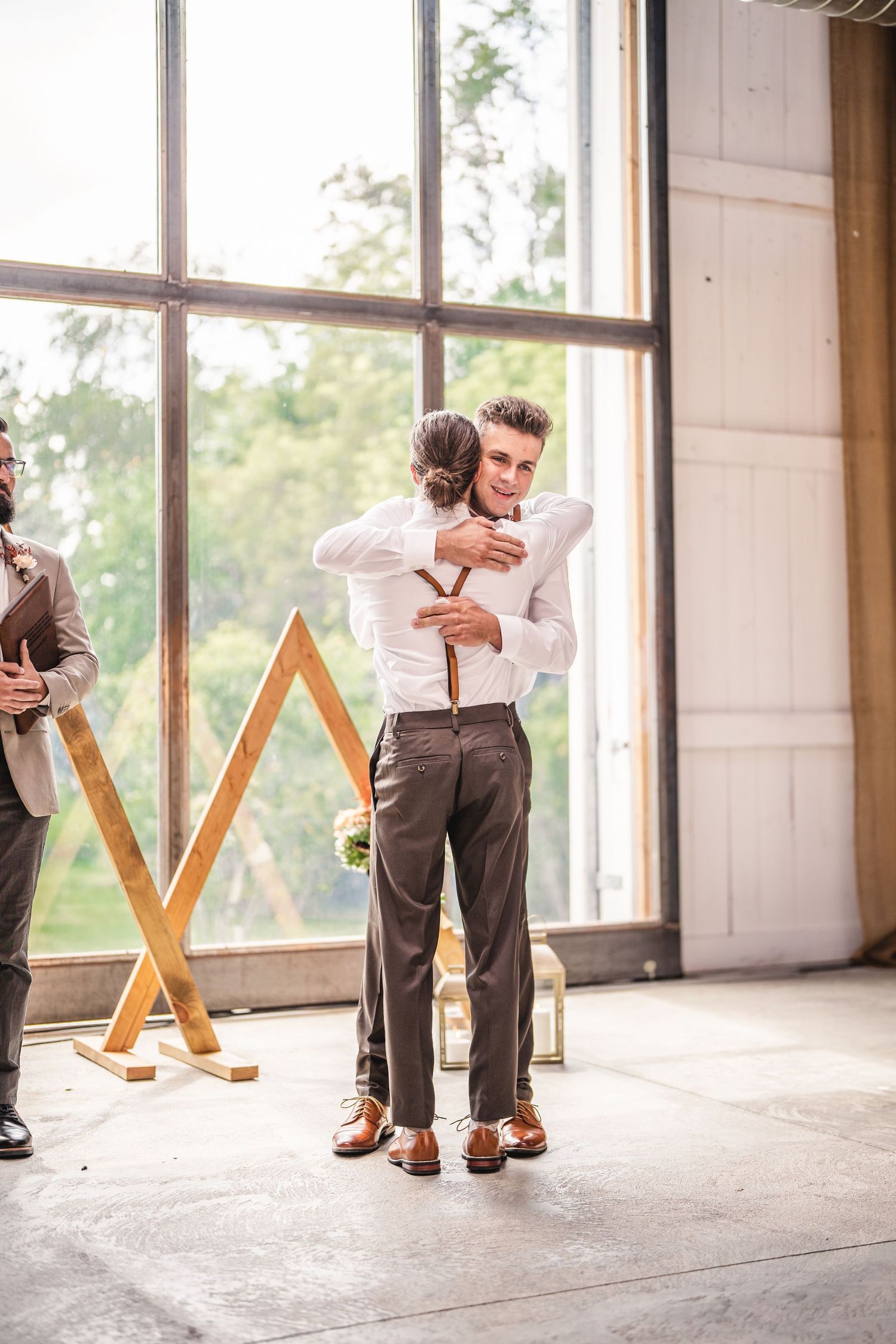 Tender moment shared in industrial wedding venue with geometric wooden backdrop.