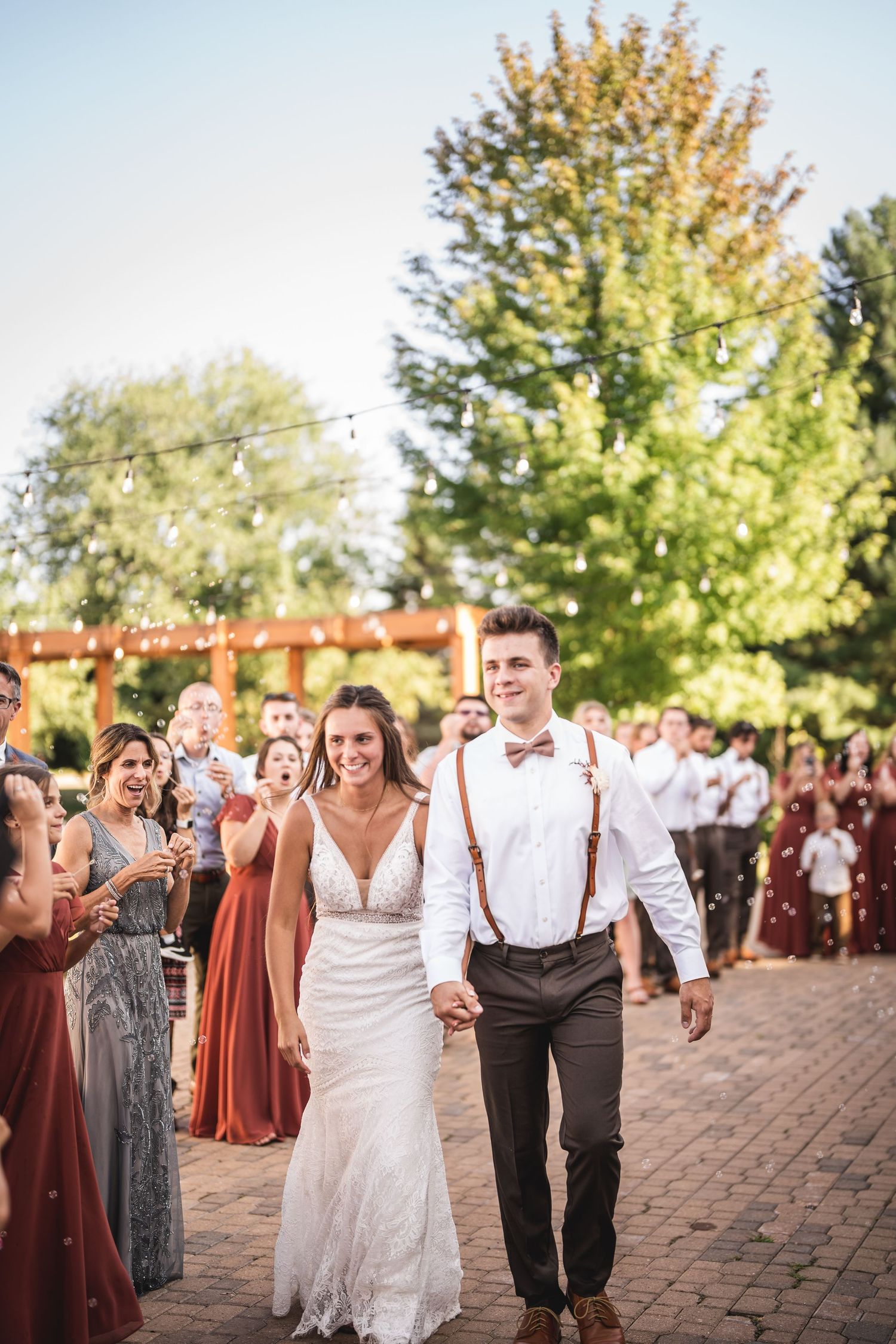 Joyful wedding celebration on brick patio with guests in burgundy dresses and white attire.