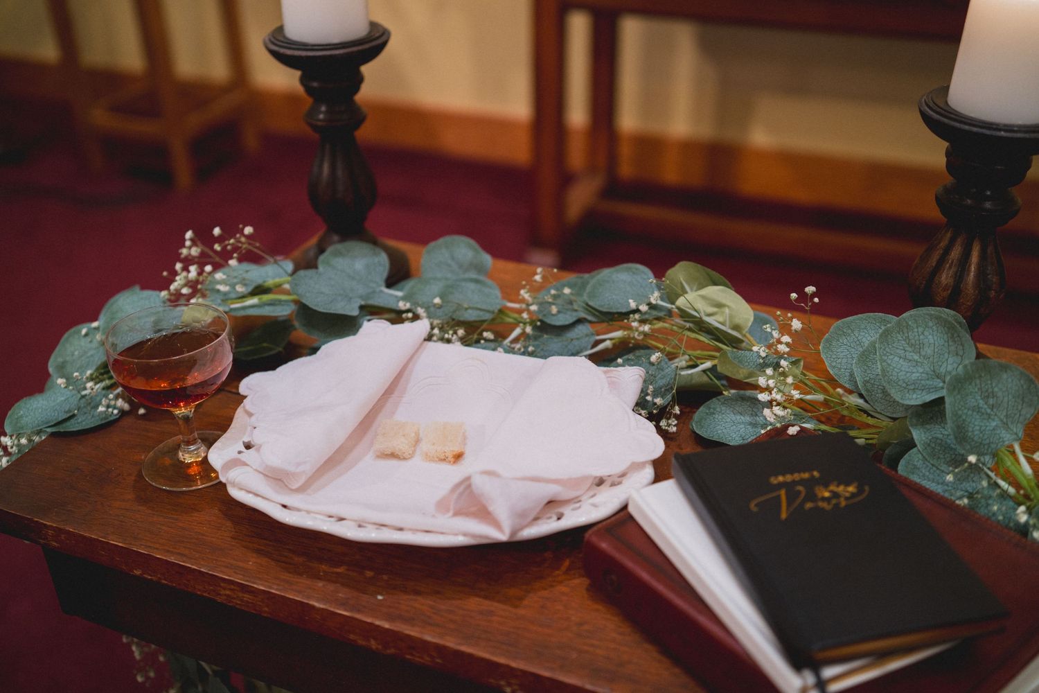 A wedding gift table decorated with eucalyptus leaves, white candles, and a guest book.