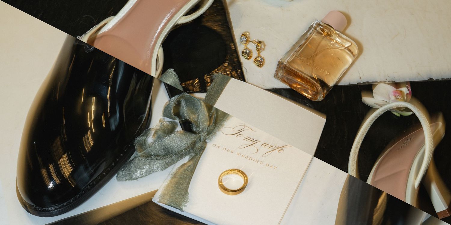 Wedding details flatlay with black patent shoes, perfume bottle, and invitation on cream background.