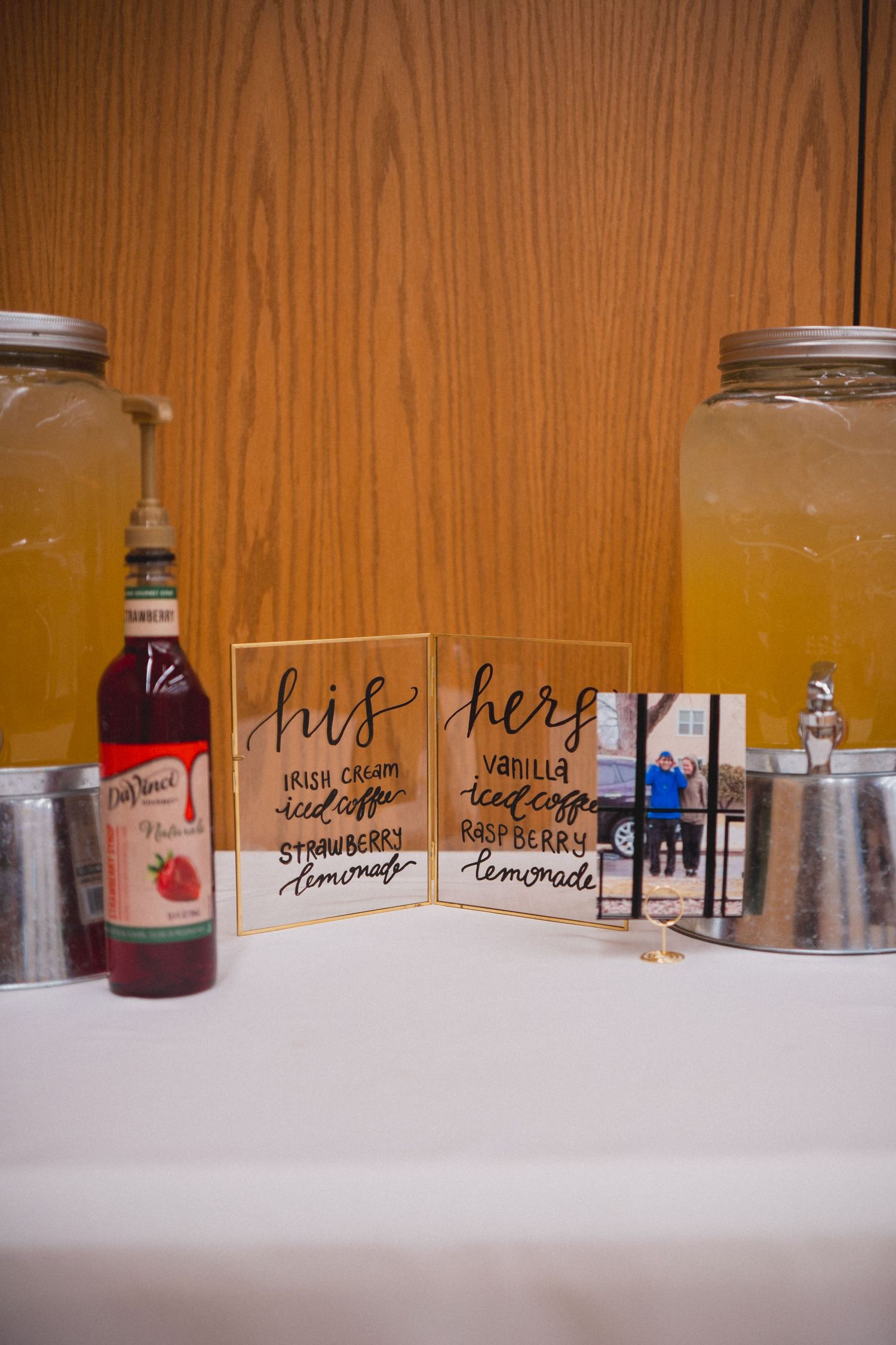 Drink dispensers with handwritten labels for various beverages at a party station.
