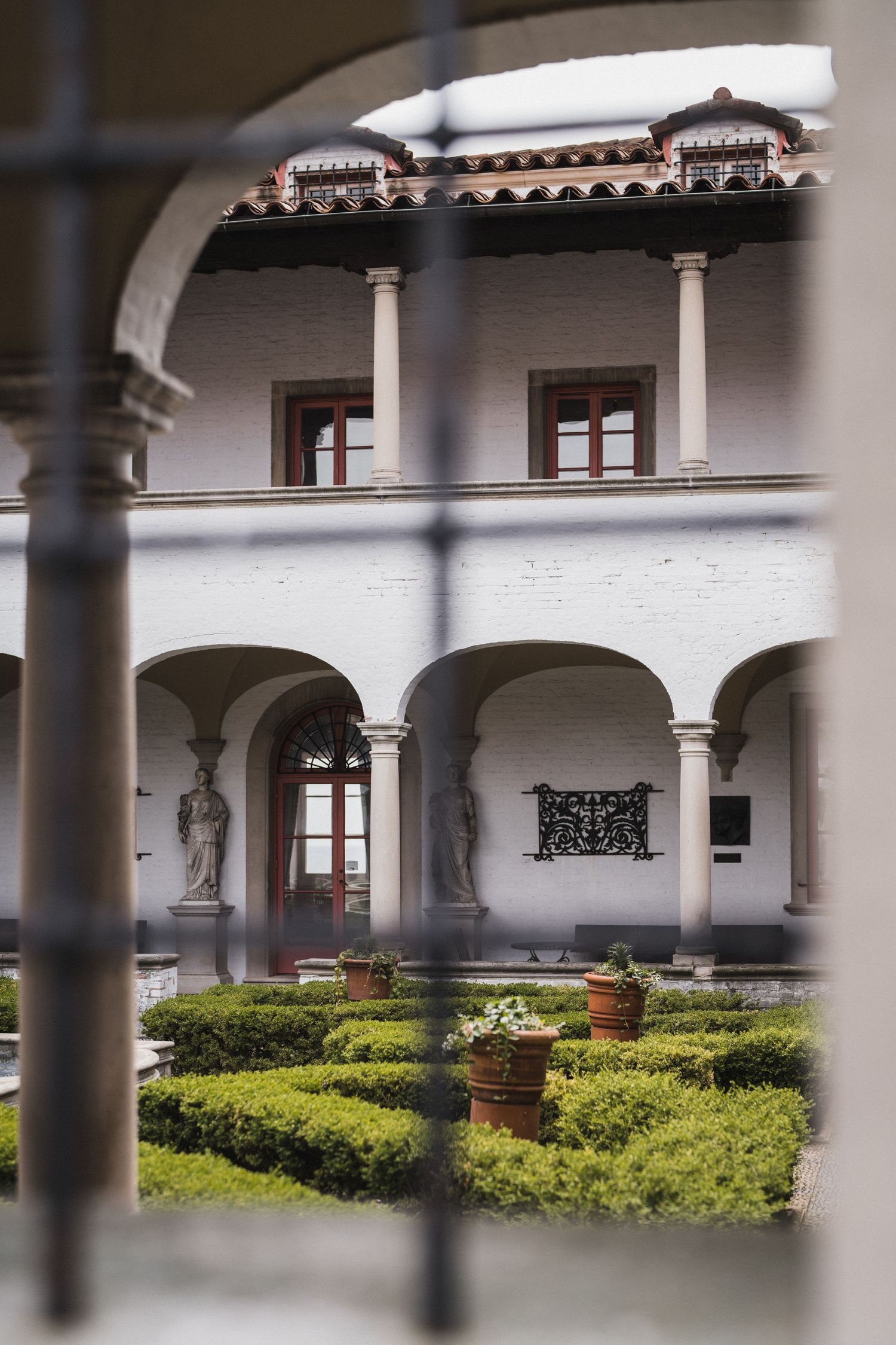 Manicured courtyard garden with white columns and Spanish-style architecture.