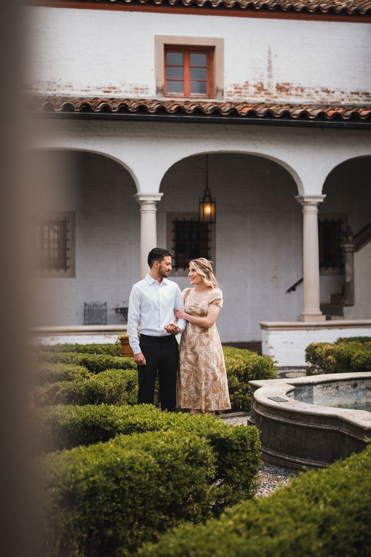 Romantic moment in a Mediterranean-style courtyard with arched walkways and greenery.