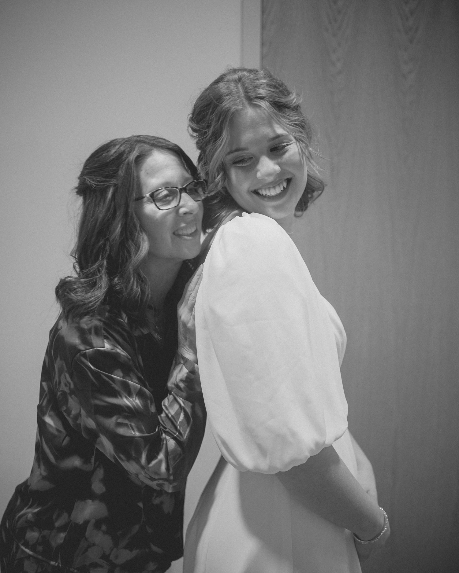 Black and white candid moment captured during wedding preparations.