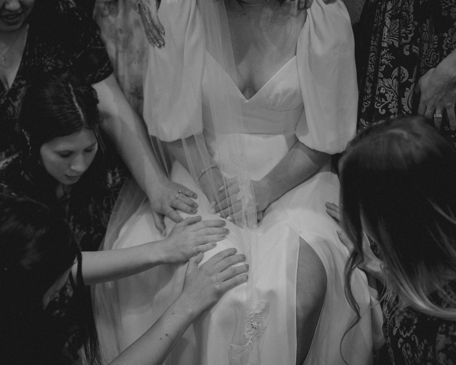 Black and white photo of bridesmaids praying together before the ceremony.