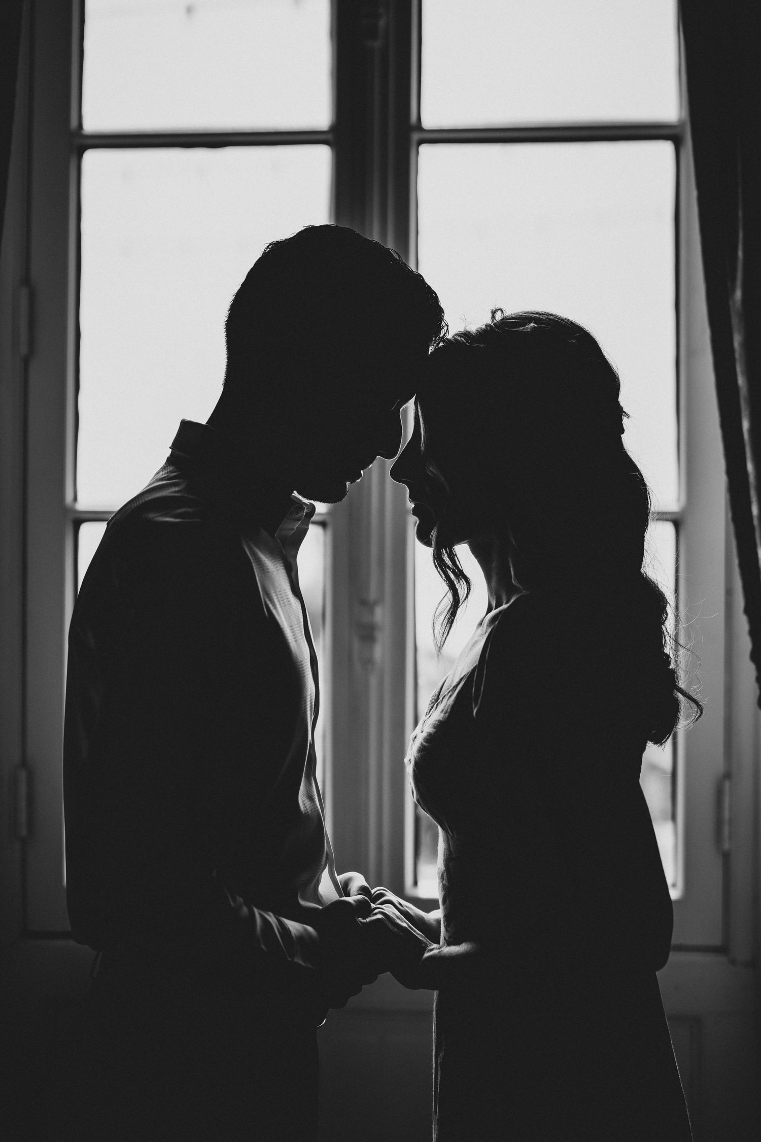 Silhouettes of people against bright windows in dramatic black and white photography.