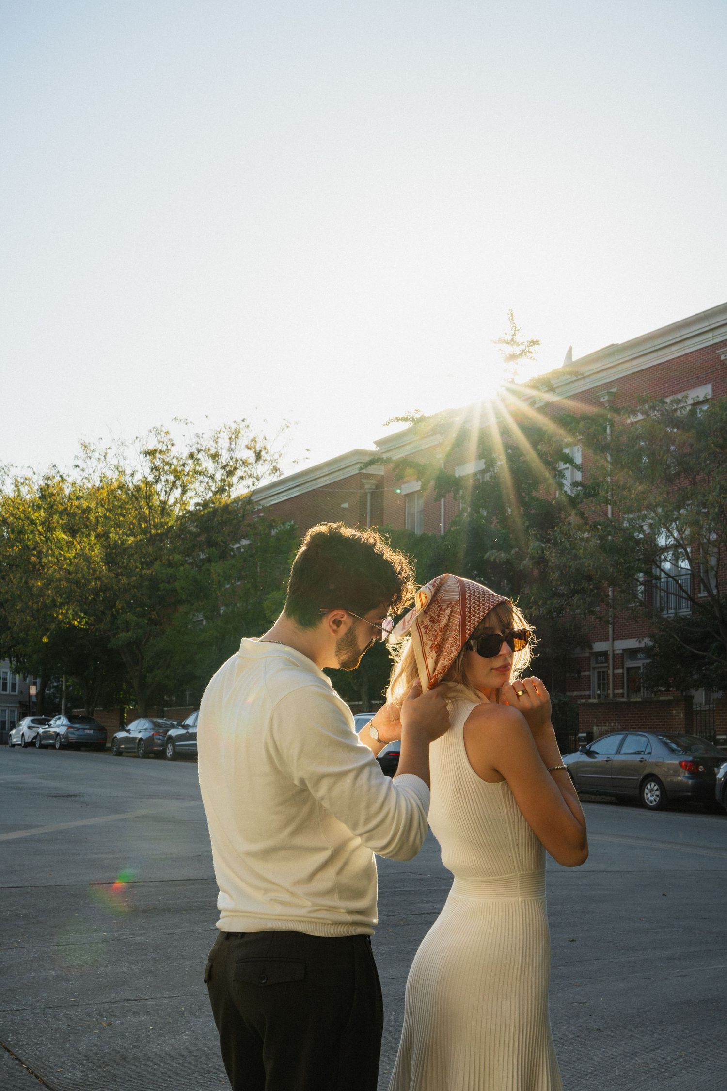 A couple sharing a playful moment in golden sunset light on a city street.