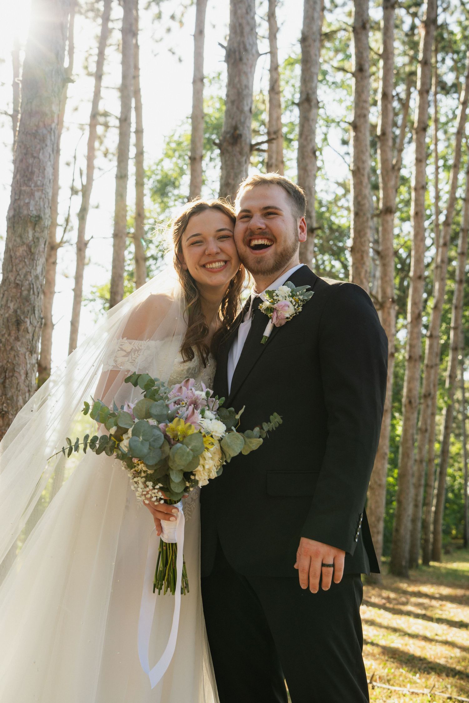 A joyful wedding moment captured in a sun-dappled forest setting.