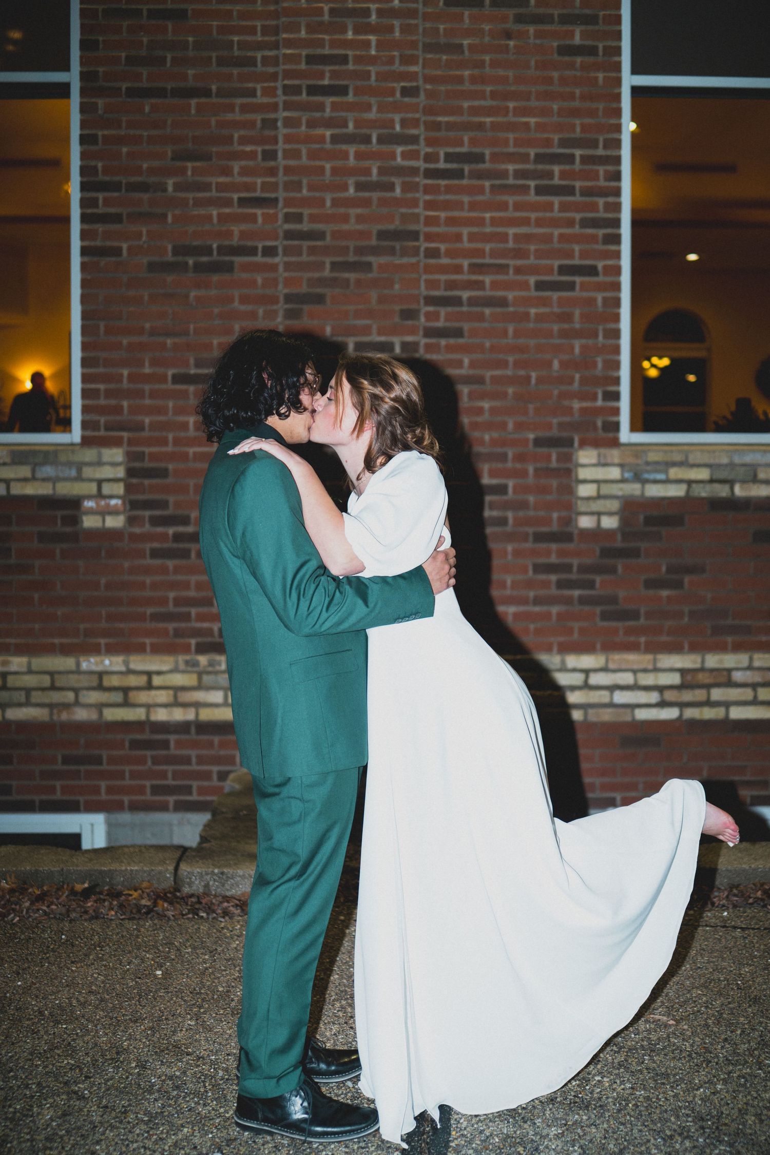 Wedding couple performs romantic dip kisses in sequence against brick building backdrop.