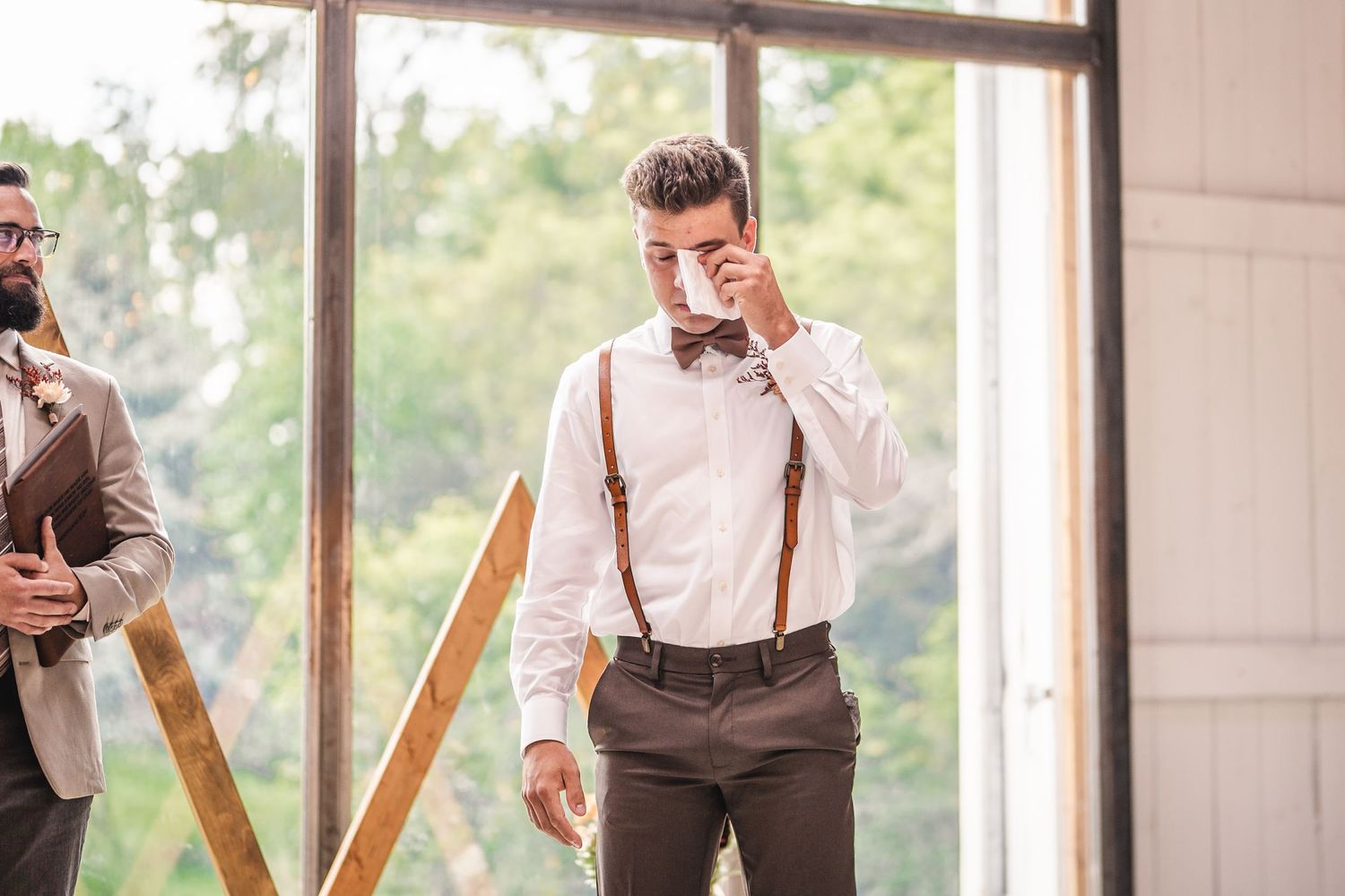 Emotional moment captured in industrial venue with large windows and wooden accents.