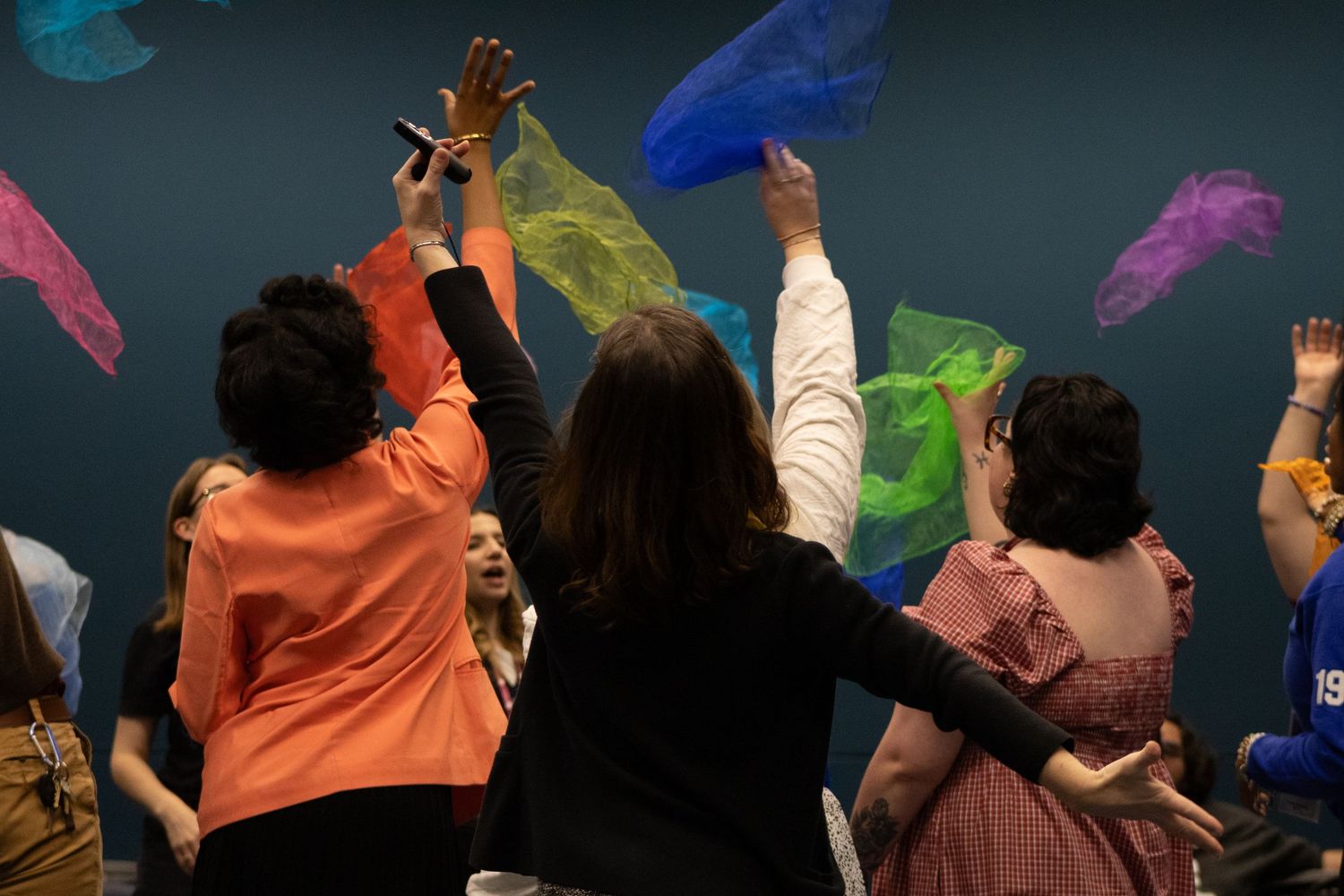 People waving colorful scarves during a performance or dance.