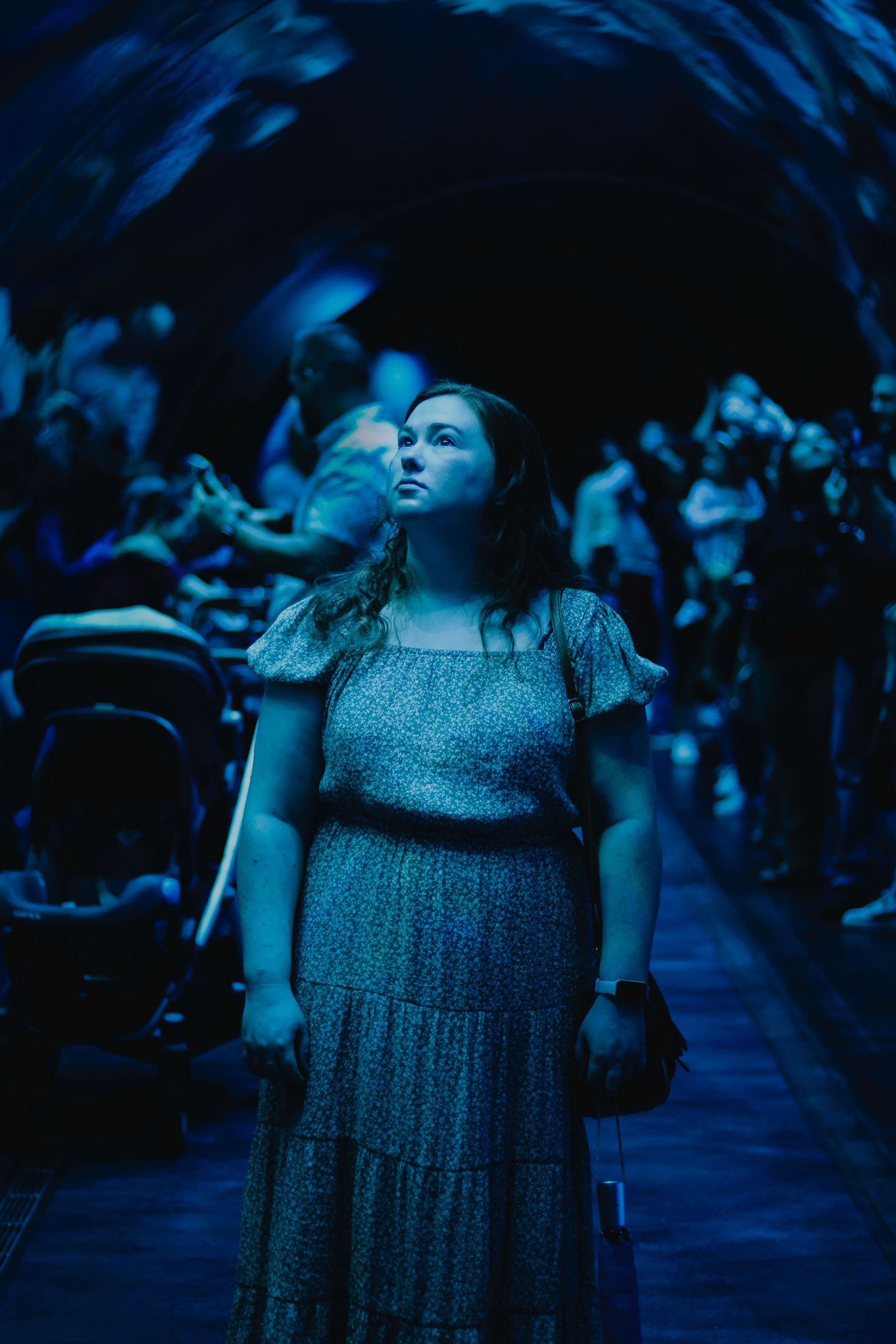 A person in a sparkly dress performs on a dimly lit stage with dramatic blue lighting.