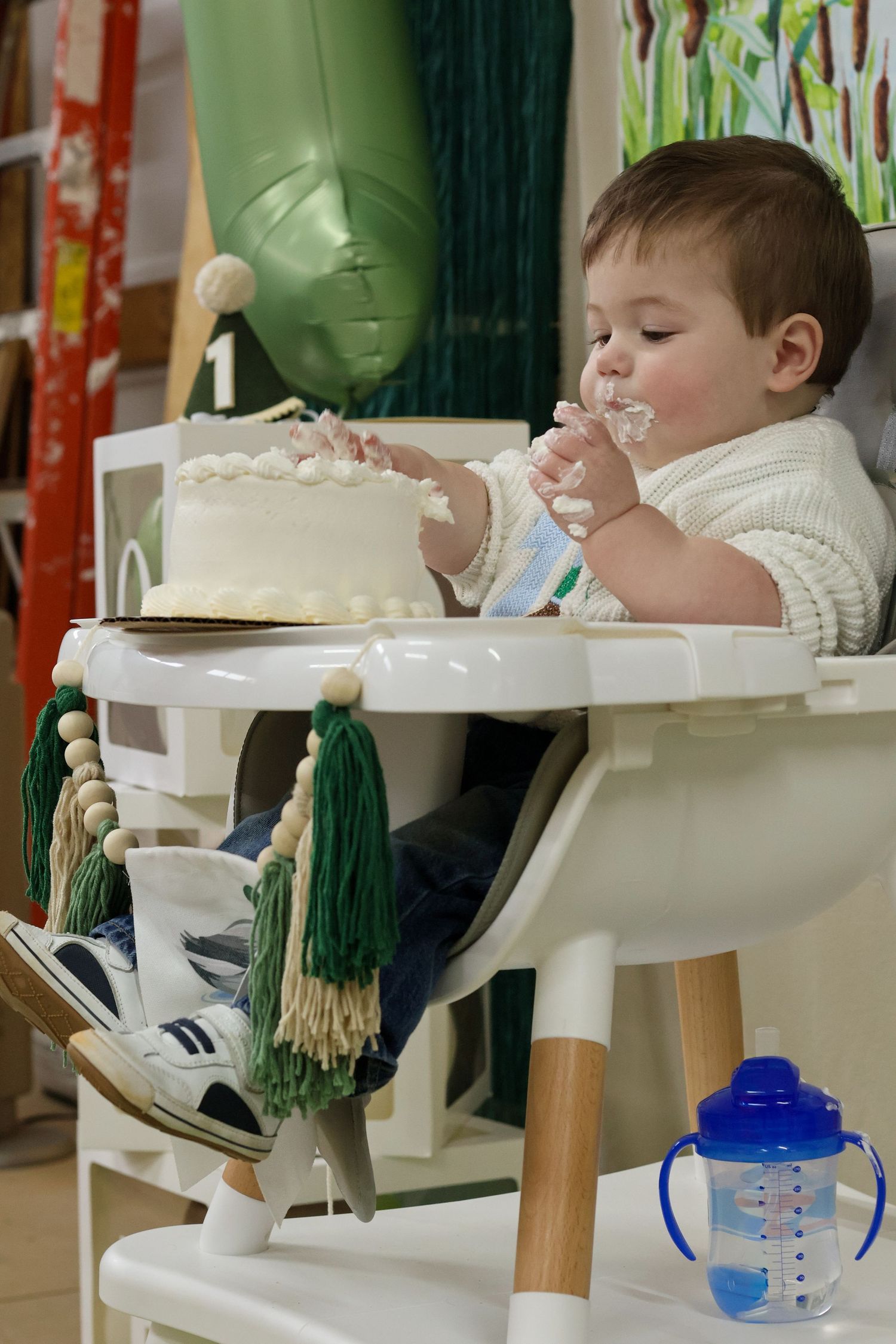 Baby in white sweater sitting in high chair during mealtime.