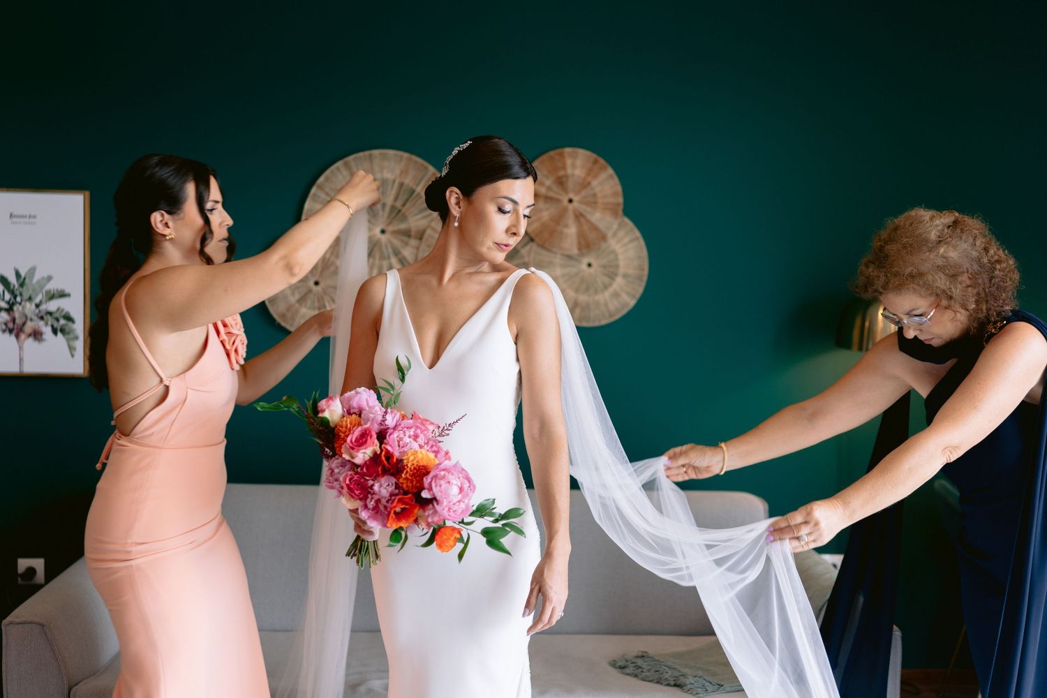 Wedding party in pink and white dresses holding bouquets against a teal background.