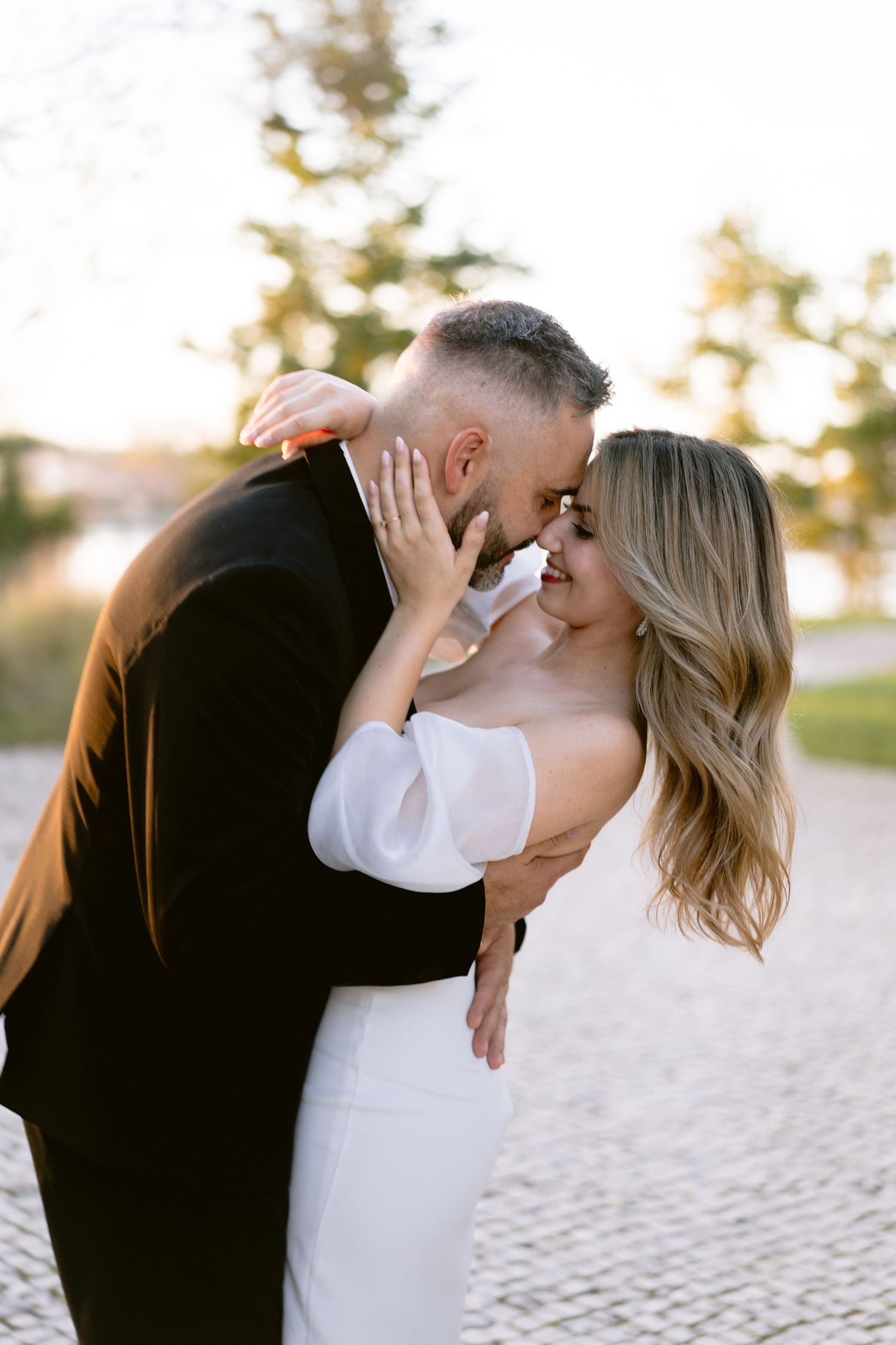 Romantic beach wedding portraits at sunset with couple in intimate embrace.