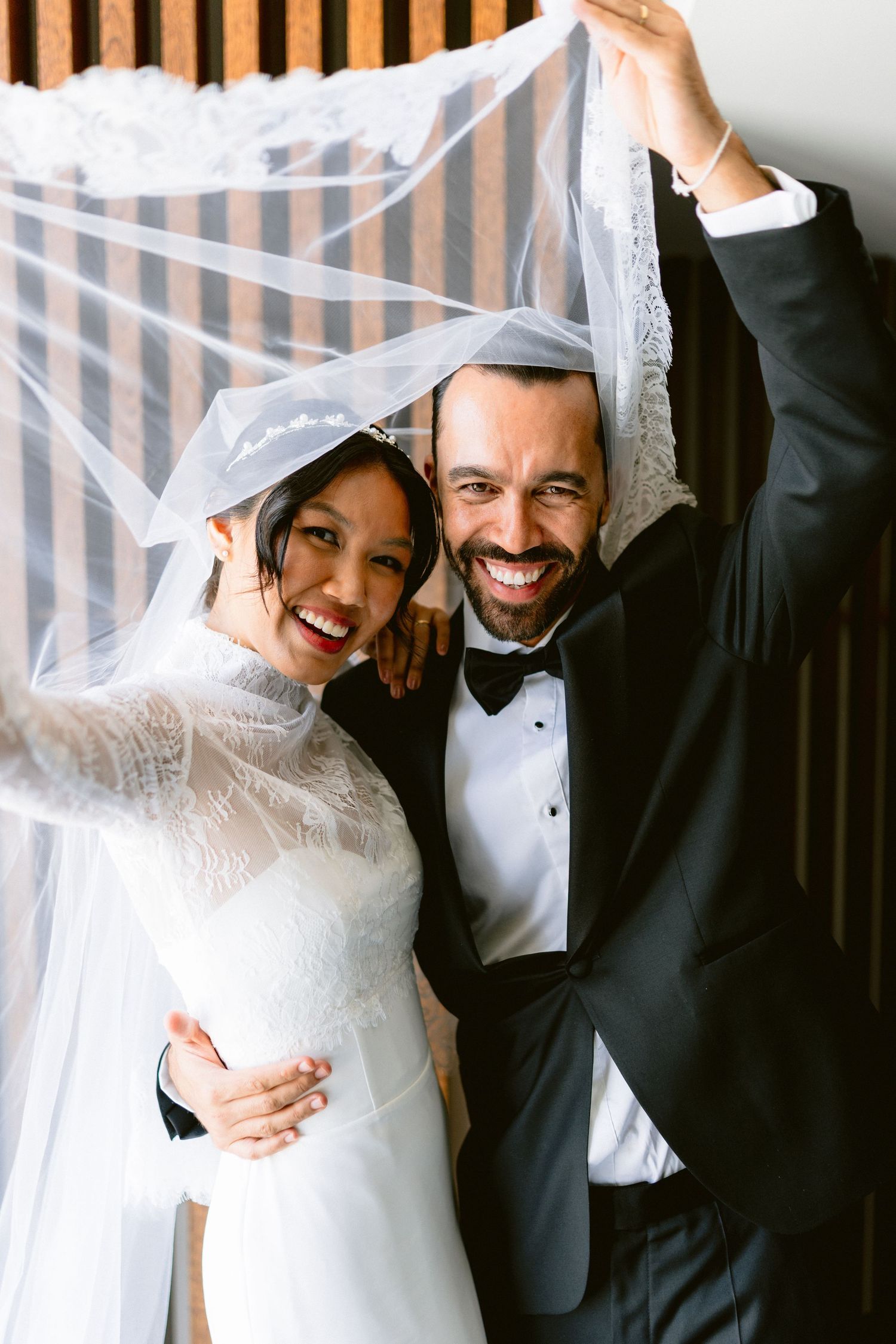 Romantic wedding portraits against a striped wall showing joyful candid moments.