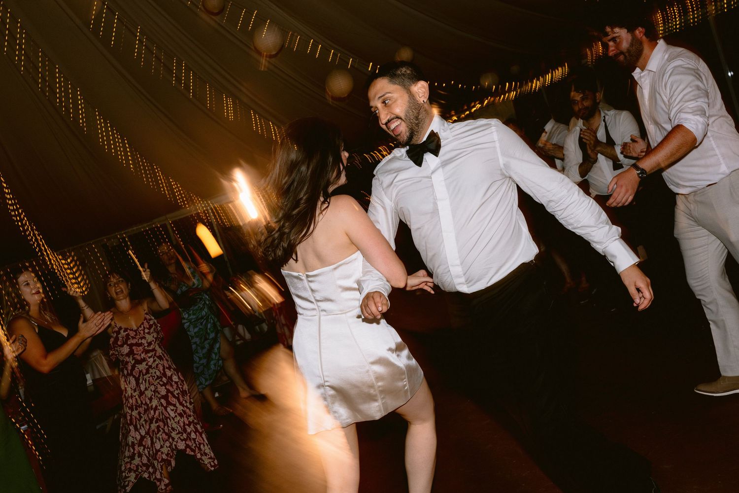 Wedding reception dance floor filled with guests celebrating under warm lighting.