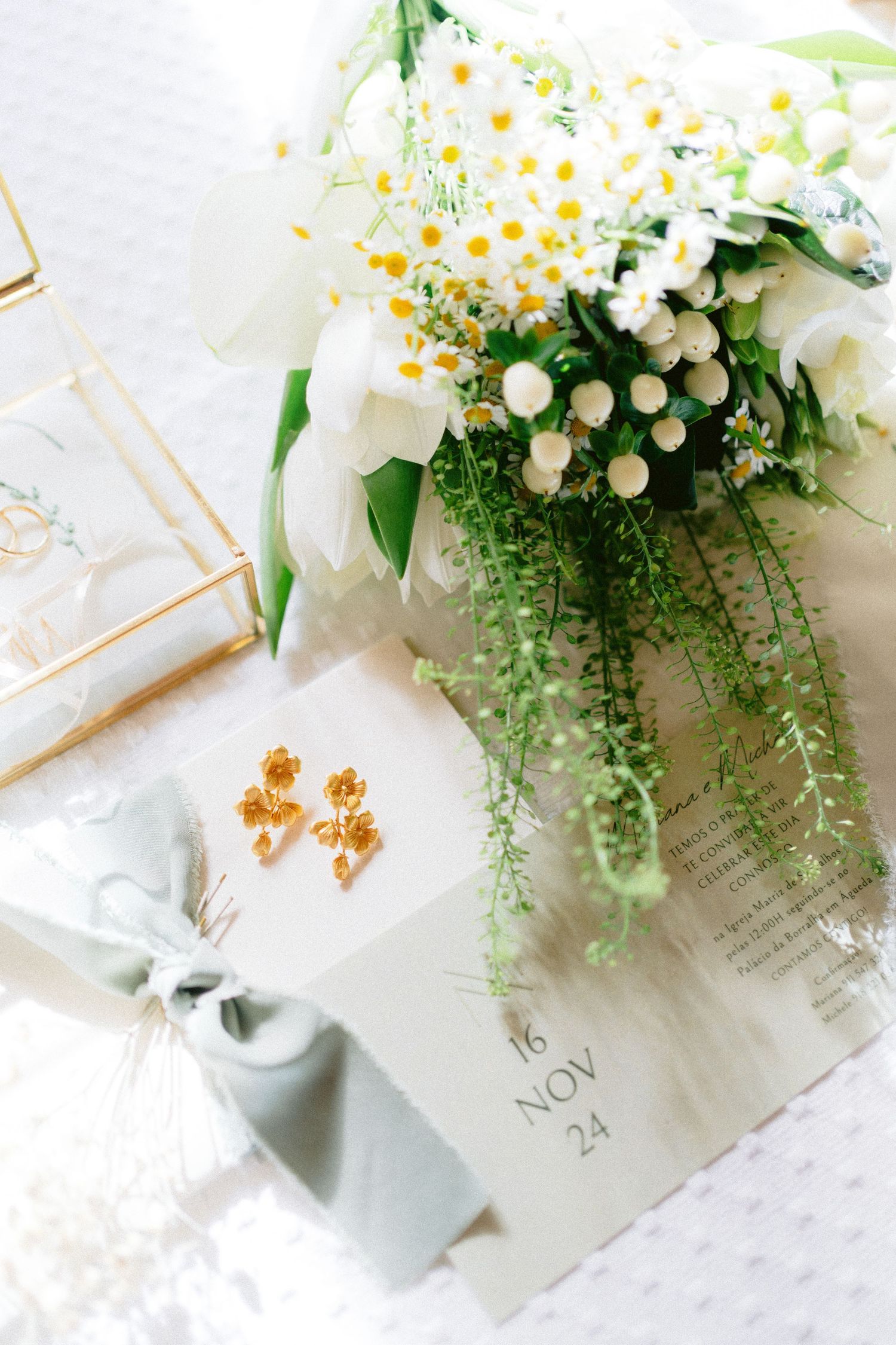 Delicate white floral arrangements with greenery displayed on wedding invitations.