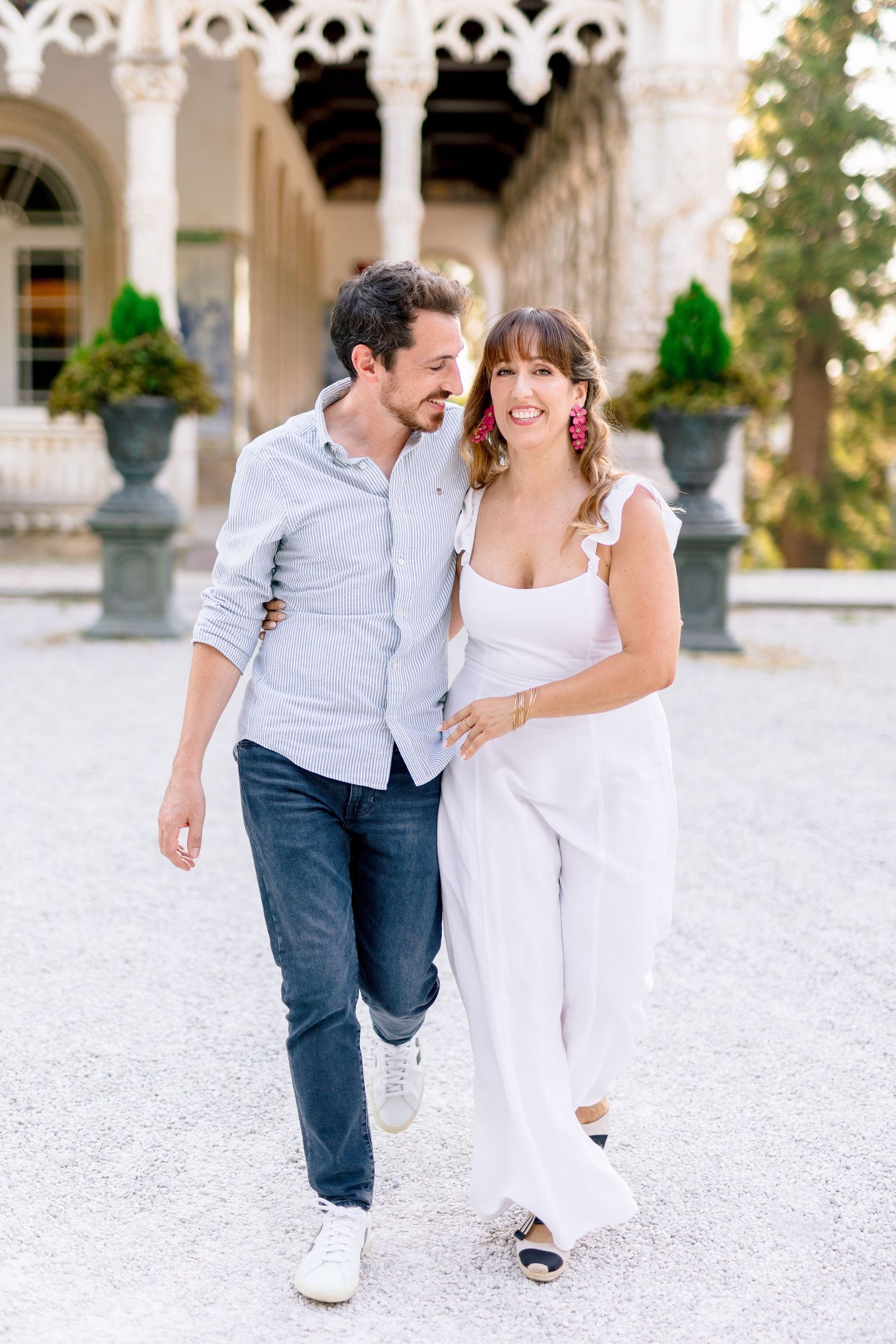 A romantic couple in casual attire shares a playful moment while running outdoors.