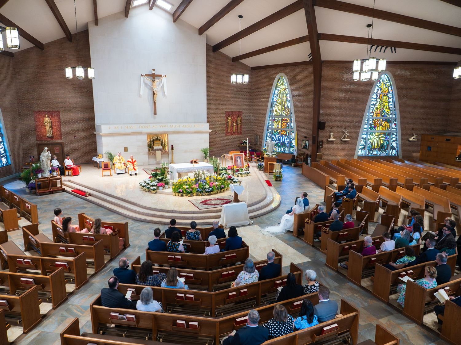 Overhead view of a Catholic church wedding ceremony with guests seated in wooden pews.
