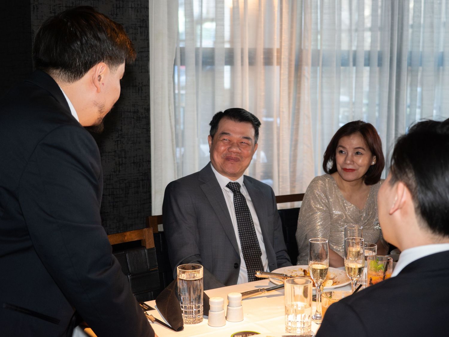 Group of Asian business professionals enjoying a formal dinner meeting at an upscale restaurant.