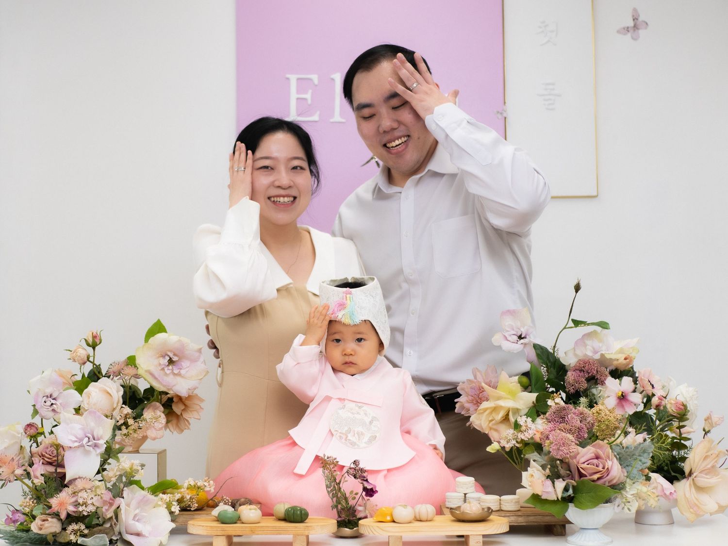 Family celebrating a baby's first birthday doljabi ceremony with flowers and traditional Korean hanbok decorations.
